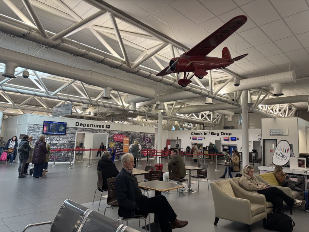 a group of people sitting in a waiting area with a model airplane