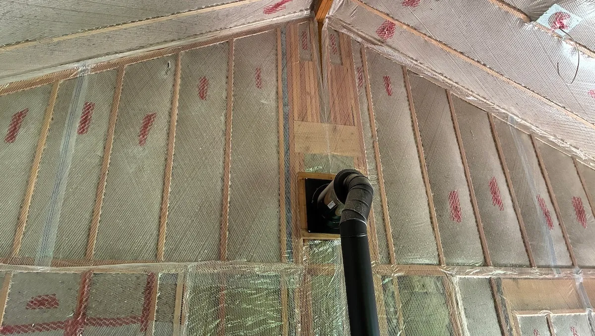 Professional insulation installer applying dense-packed cellulose insulation in an open residential wall cavity of a Connecticut home, showing clean work conditions and energy efficiency upgrades in progress.