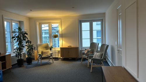 Modern schwarzer Ledersessel mit passendem Hocker in einer kleinen Leseecke mit mehreren Naturfotografien an den Wänden.
