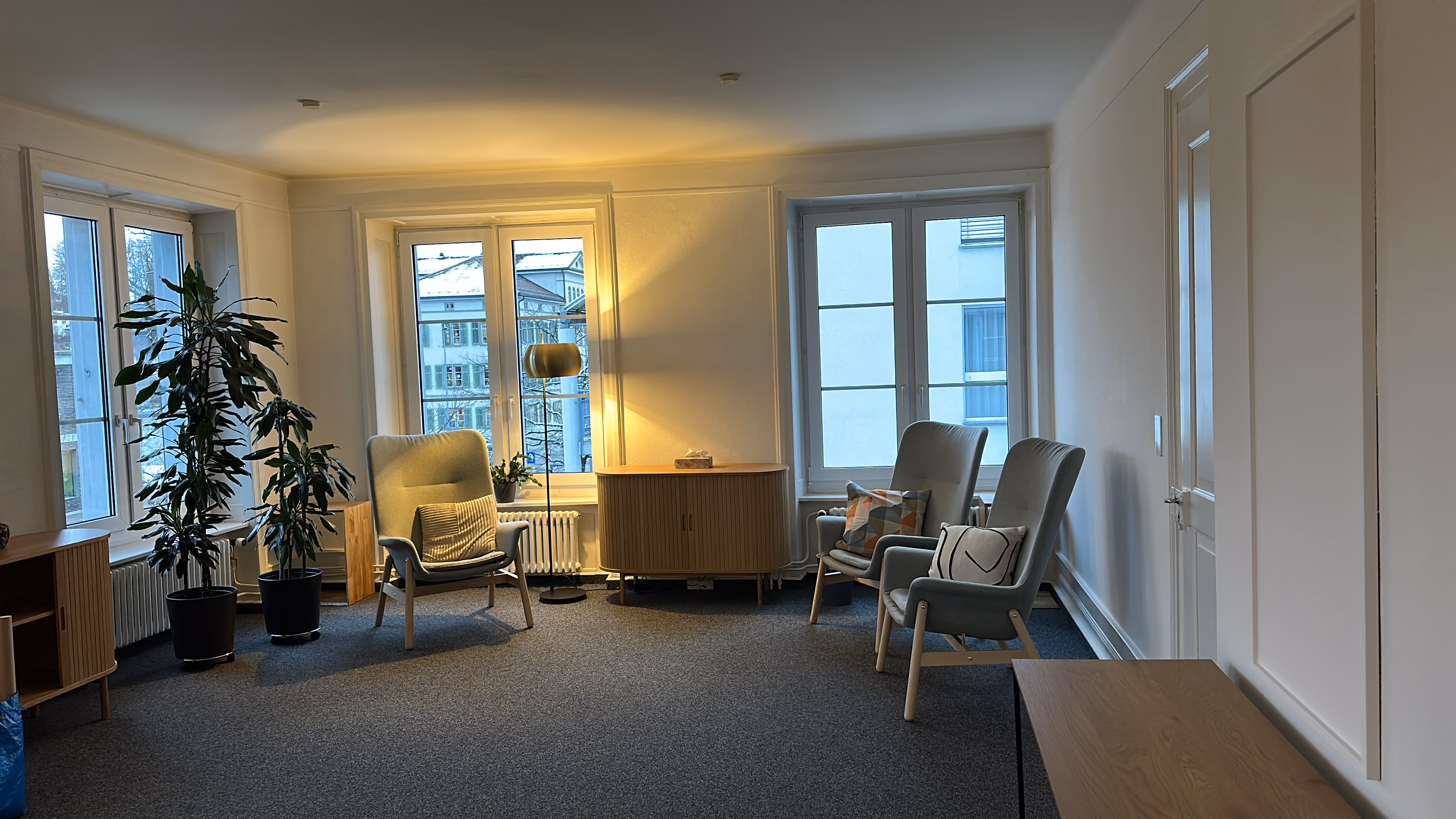 Modern schwarzer Ledersessel mit passendem Hocker in einer kleinen Leseecke mit mehreren Naturfotografien an den Wänden.