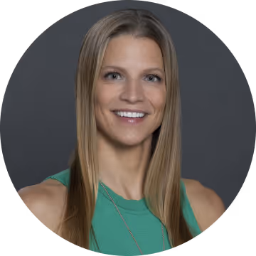 Smiling woman with long straight hair wearing a green sleeveless top against a dark gray background.