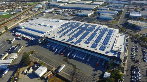 Commercial flat roof with large-scale solar panel installation on an industrial warehouse.