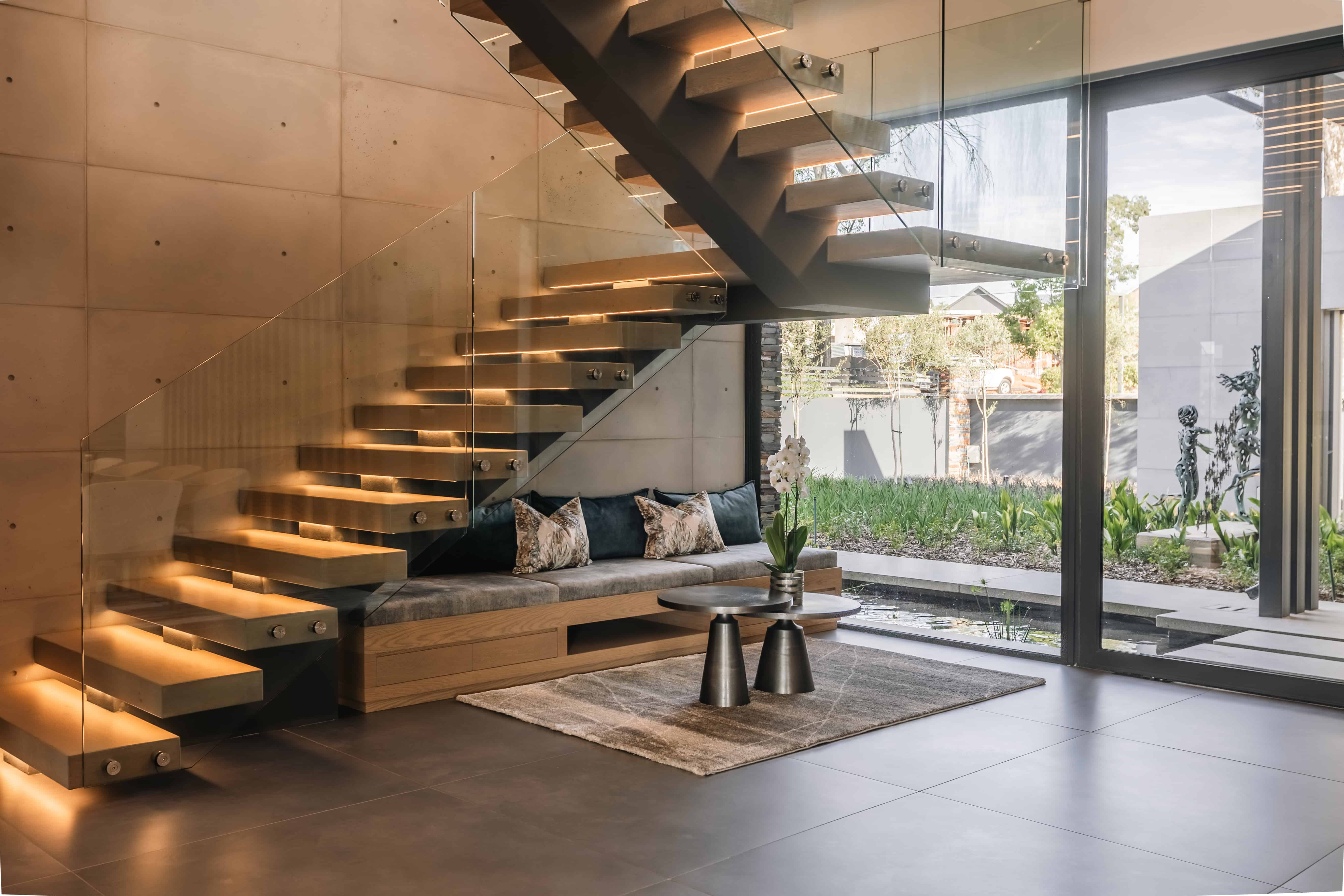 Floating timber staircase in double-volume entrance of Steyn City luxury home by Renovatio Interiors Johannesburg.