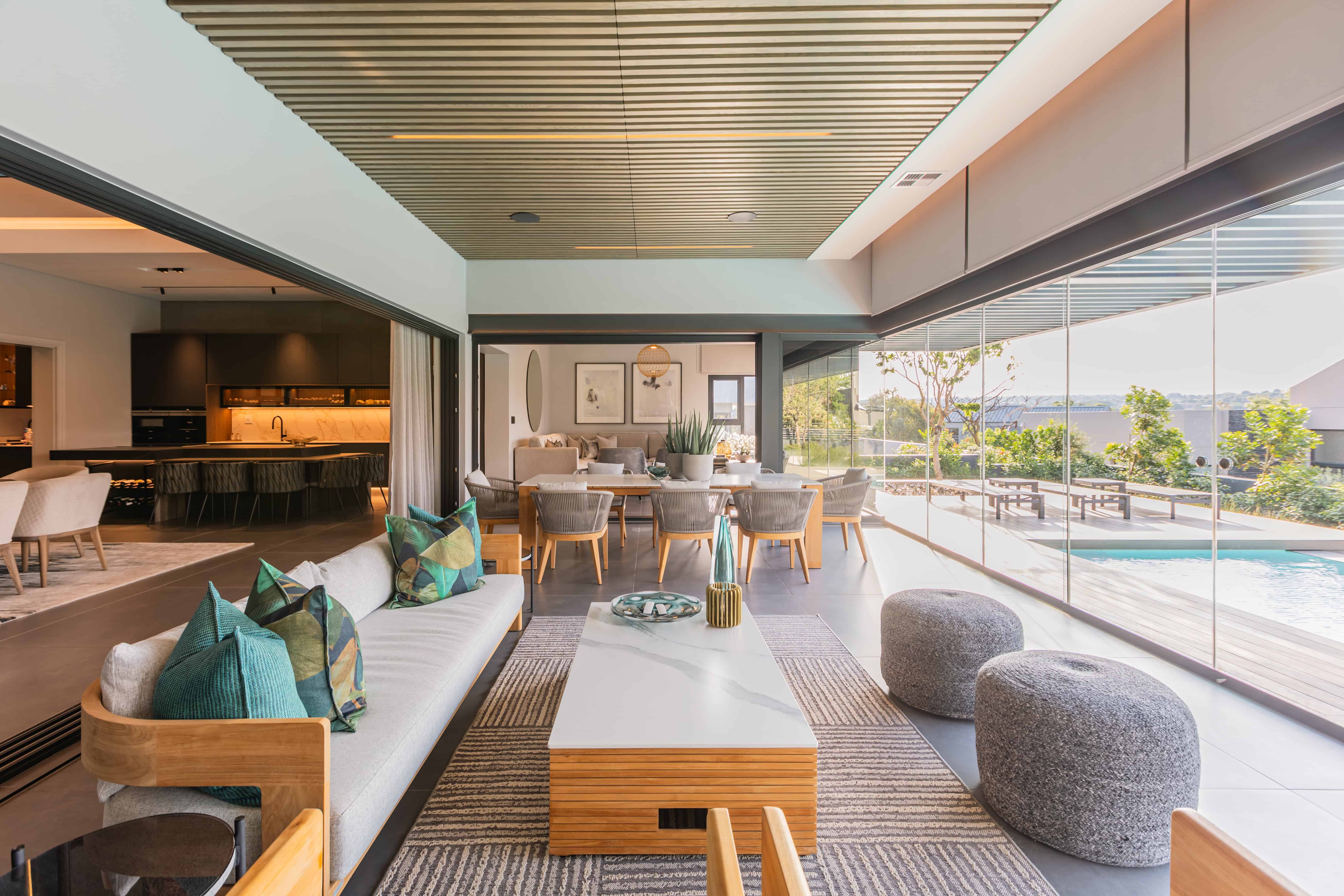 Covered patio and entertainment terrace overlooking pool in Steyn City luxury home – Johannesburg interior designer Renovatio.