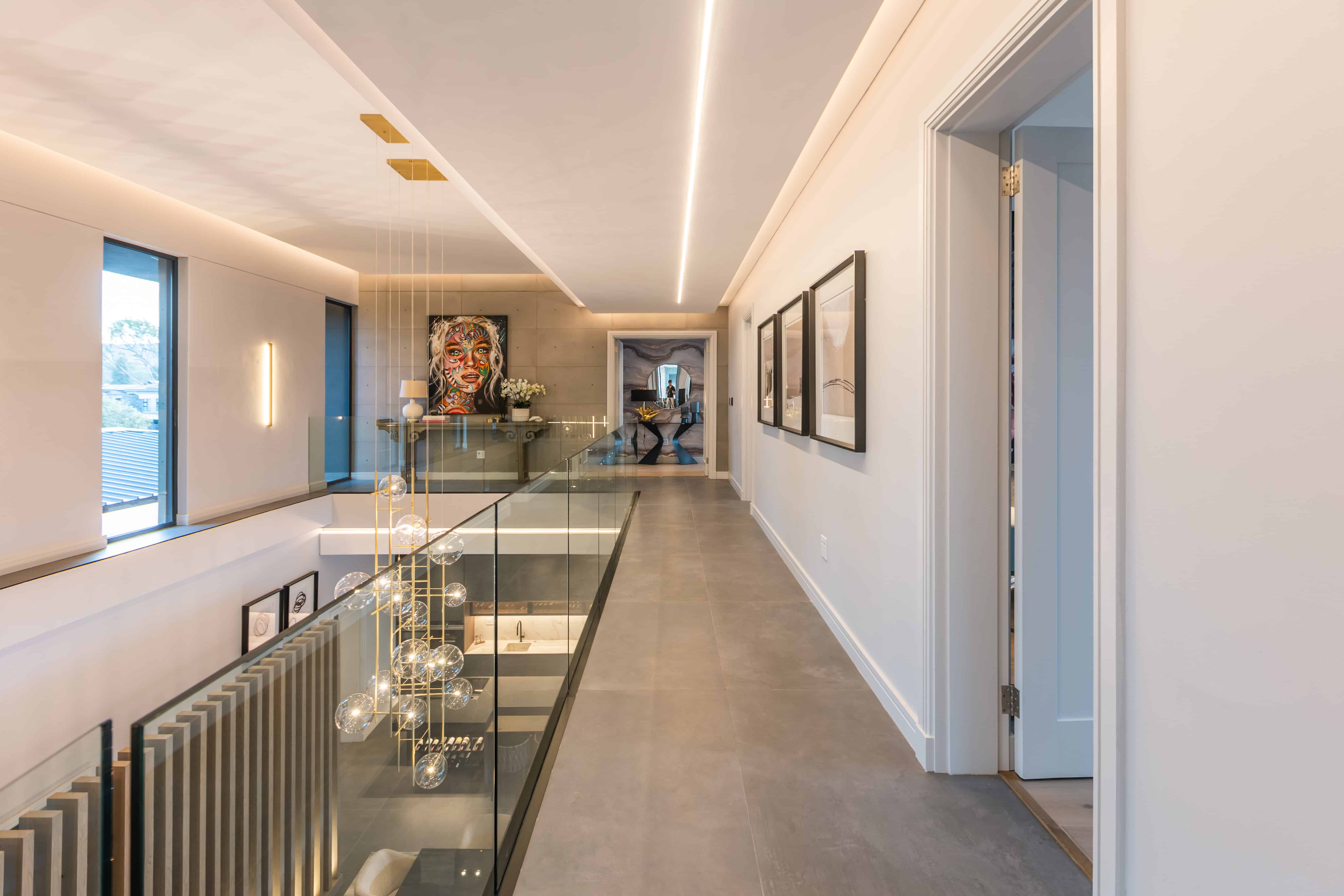 Upper landing with glass balustrade overlooking living area, Steyn City – Johannesburg interior designer.