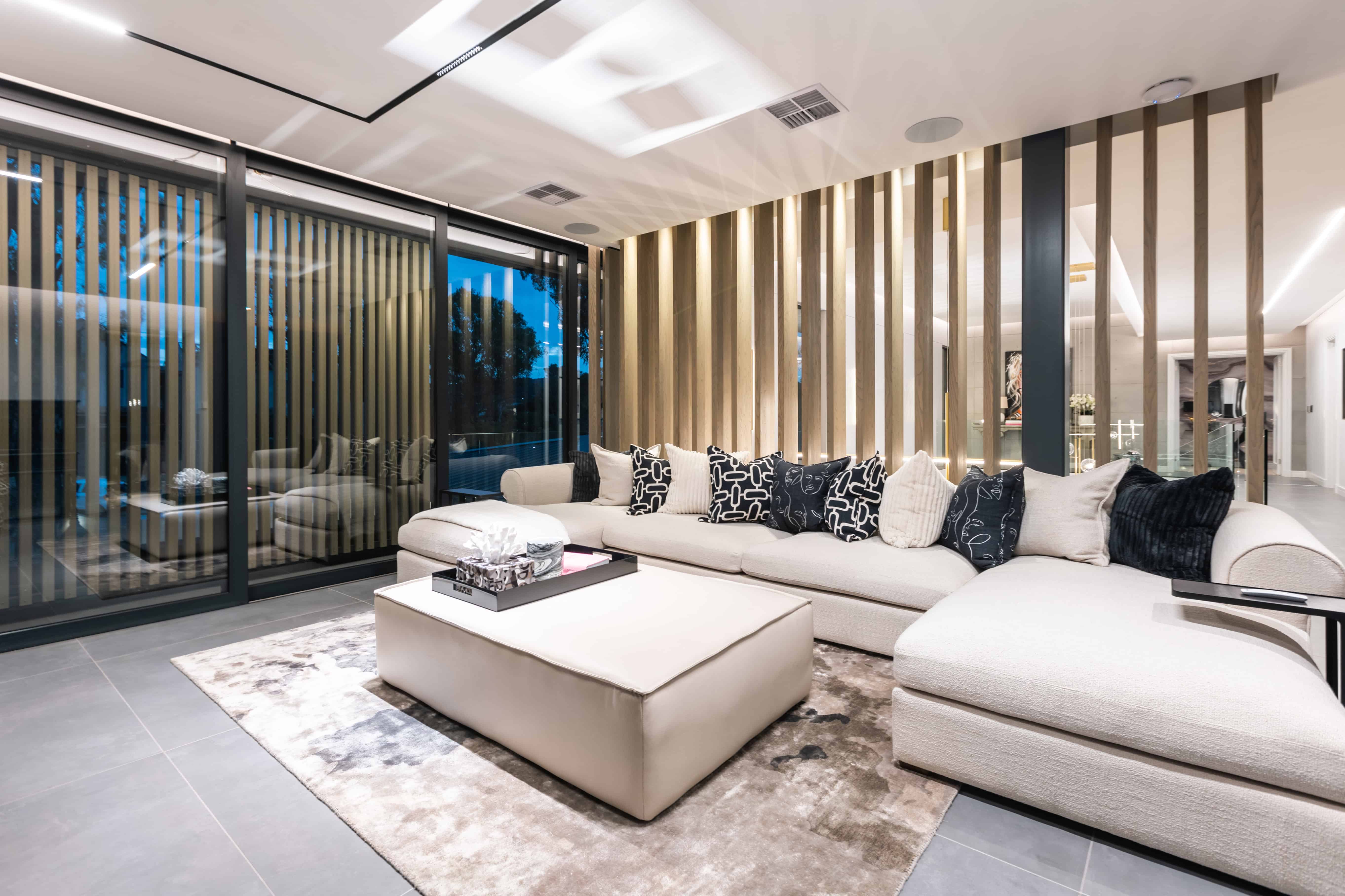 Warm, textured living room with feature slat wall and sectional sofa, Steyn City – Johannesburg interior designer.