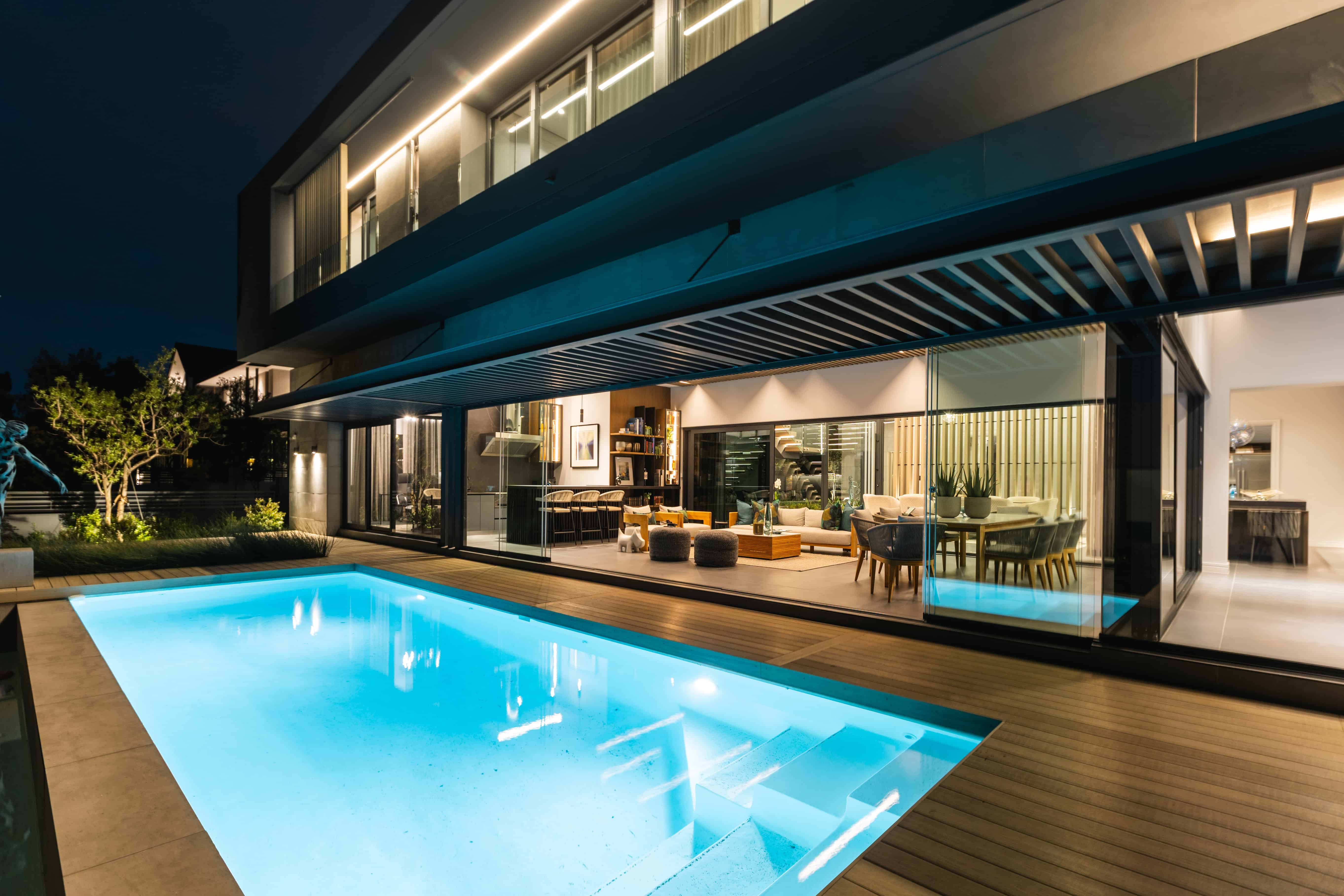 Contemporary pool area with deck lighting and architectural overhang, Steyn City residence – Renovatio Interior Design Johannesburg.