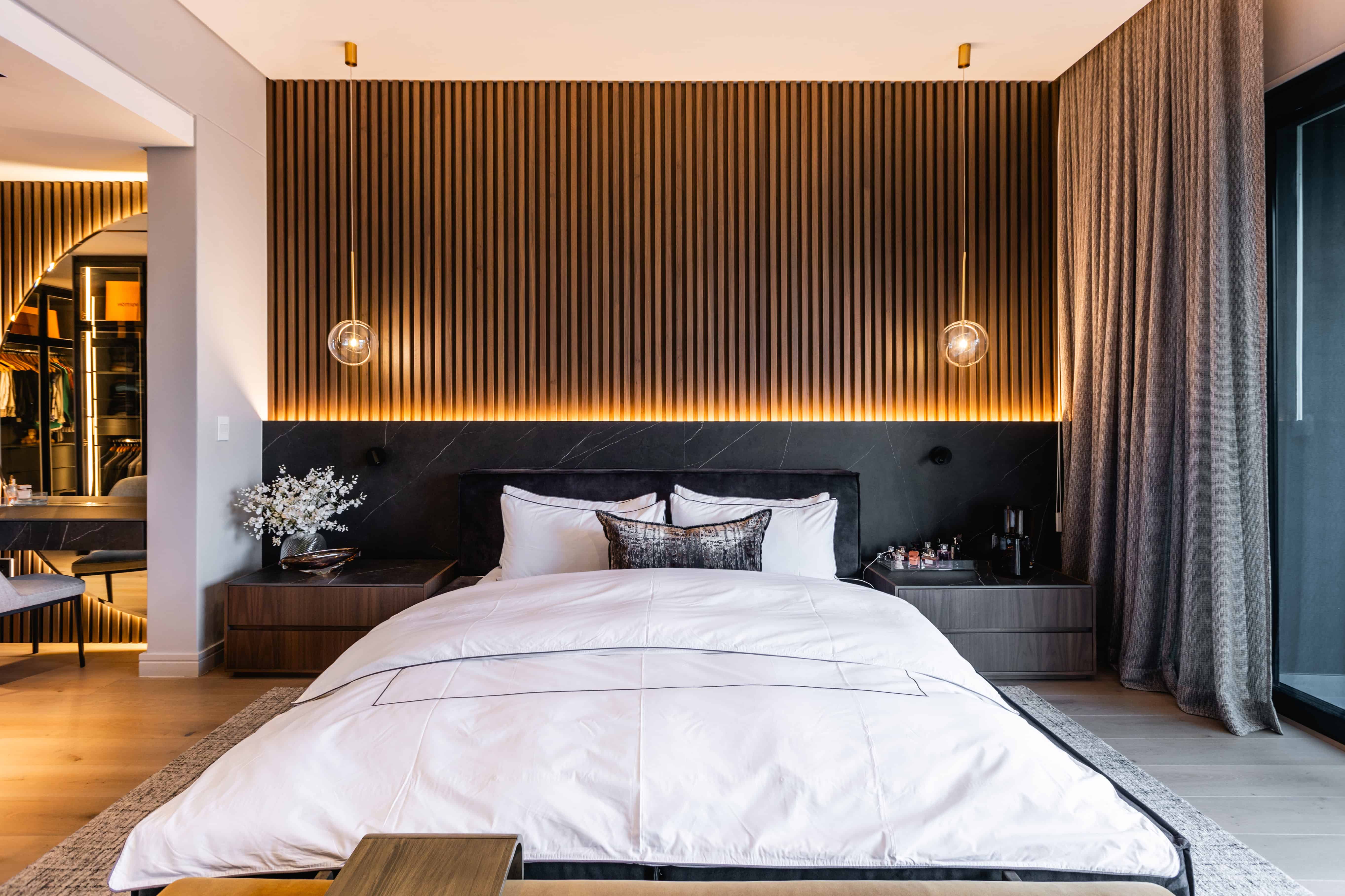 Master bedroom with textured wall panels, pendant lighting, and neutral palette in Steyn City luxury home – Johannesburg interior designer.