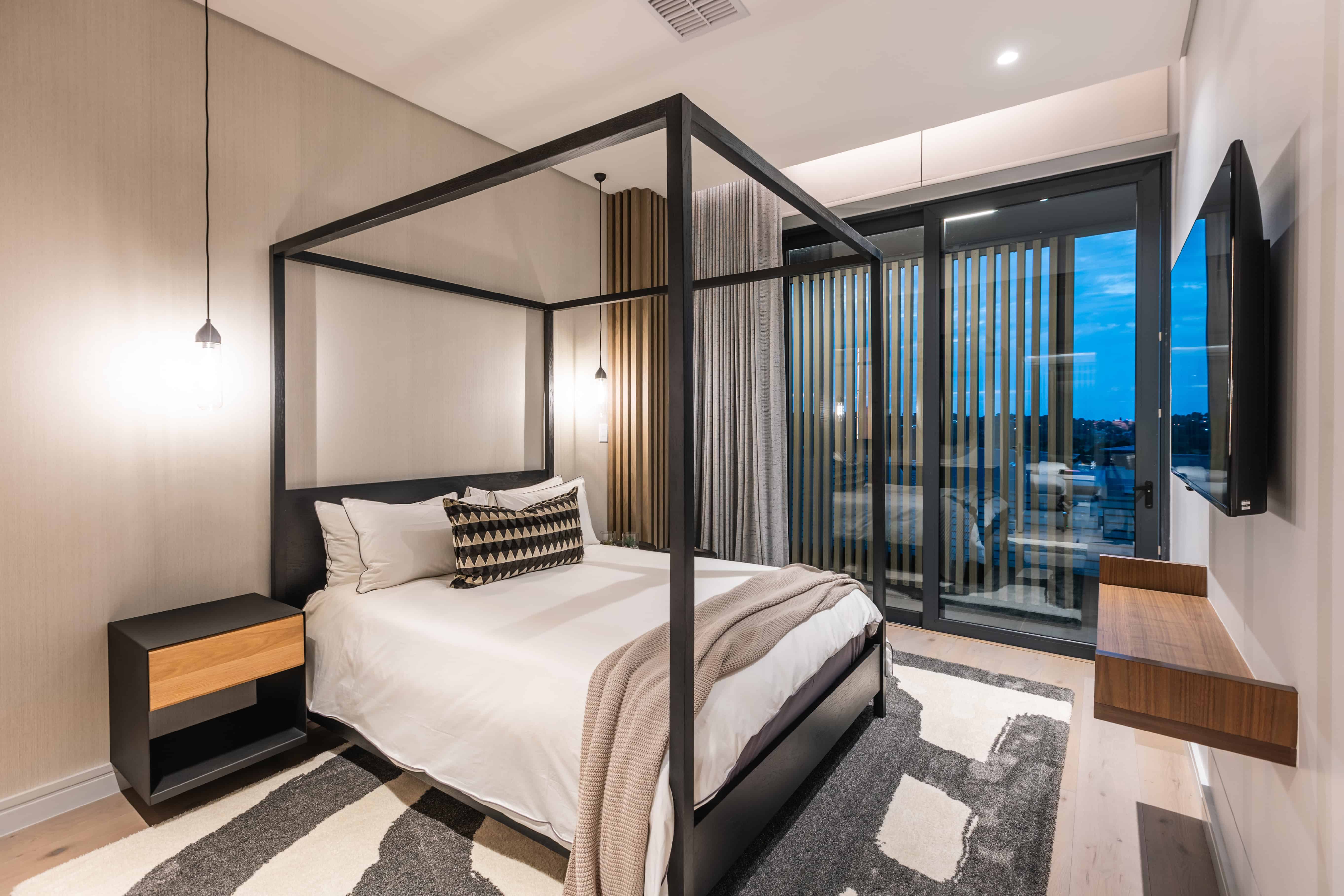 Guest suite with four-poster bed and ambient wall lighting, Steyn City – Renovatio Interiors Johannesburg.
