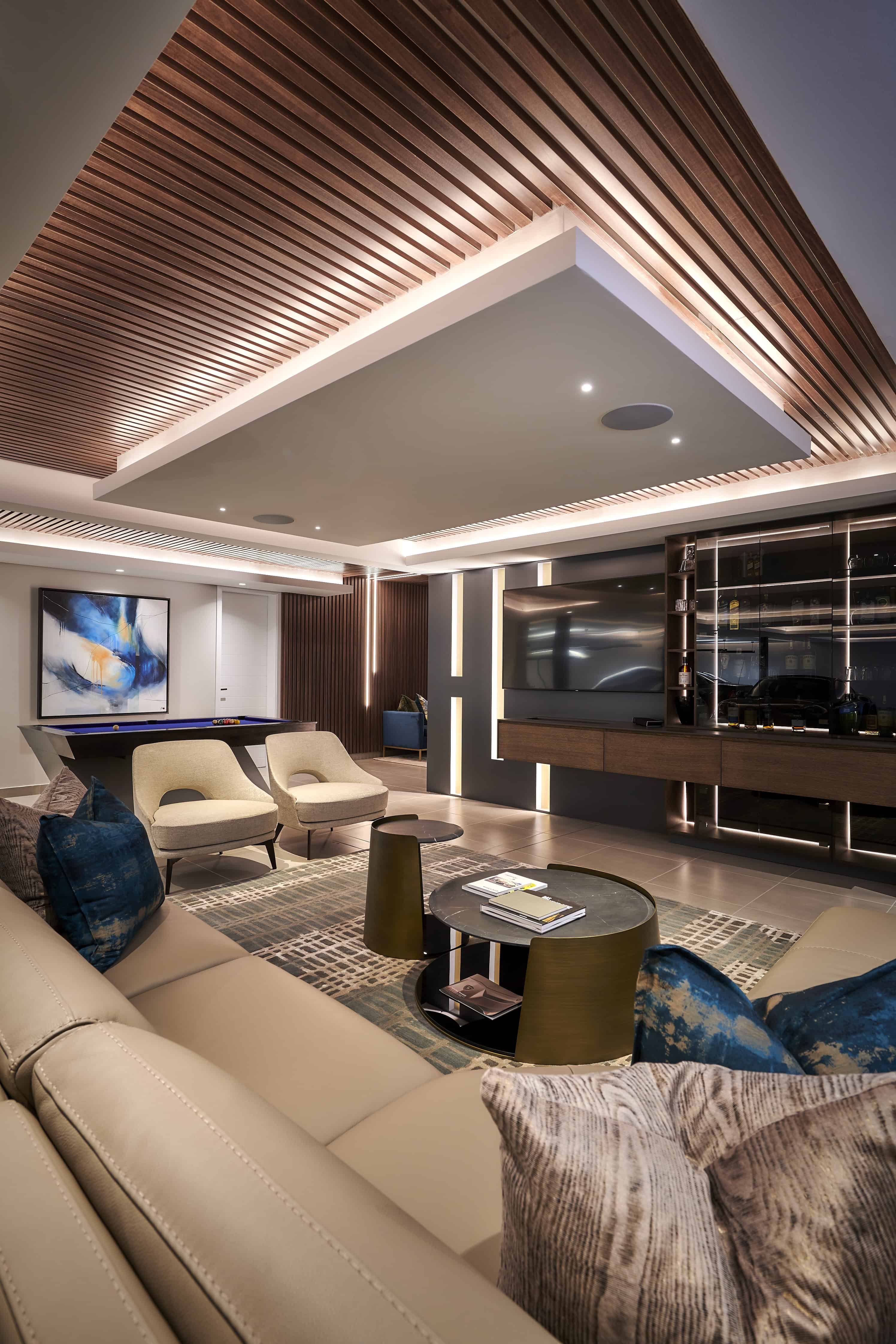 Open-plan entertainment area with vaulted ceiling, plush seating and feature wall designed by Interior Designer Johannesburg.