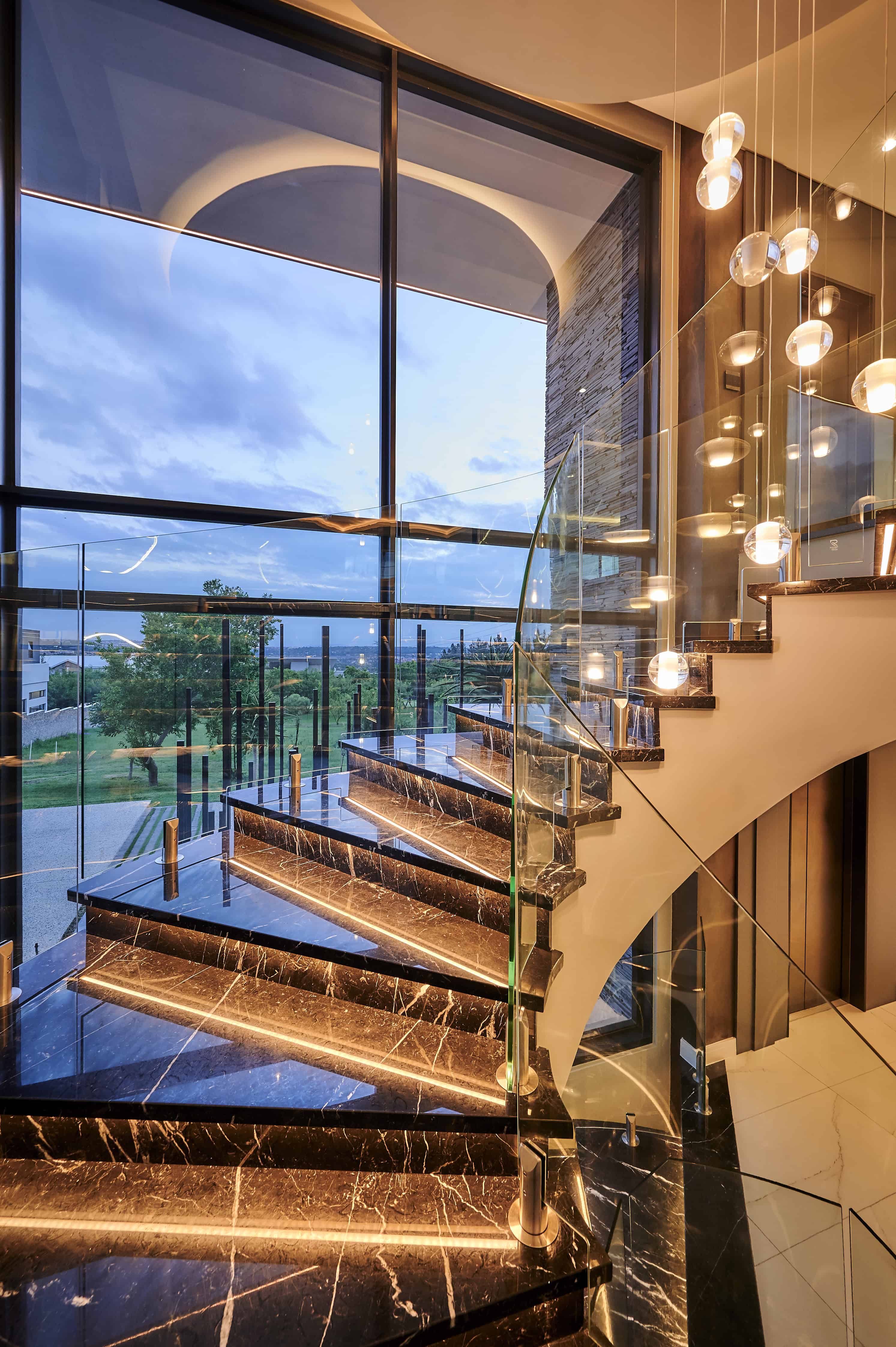 Modern staircase with glass balustrade and hanging light fixture designed by Interior Designer Johannesburg.