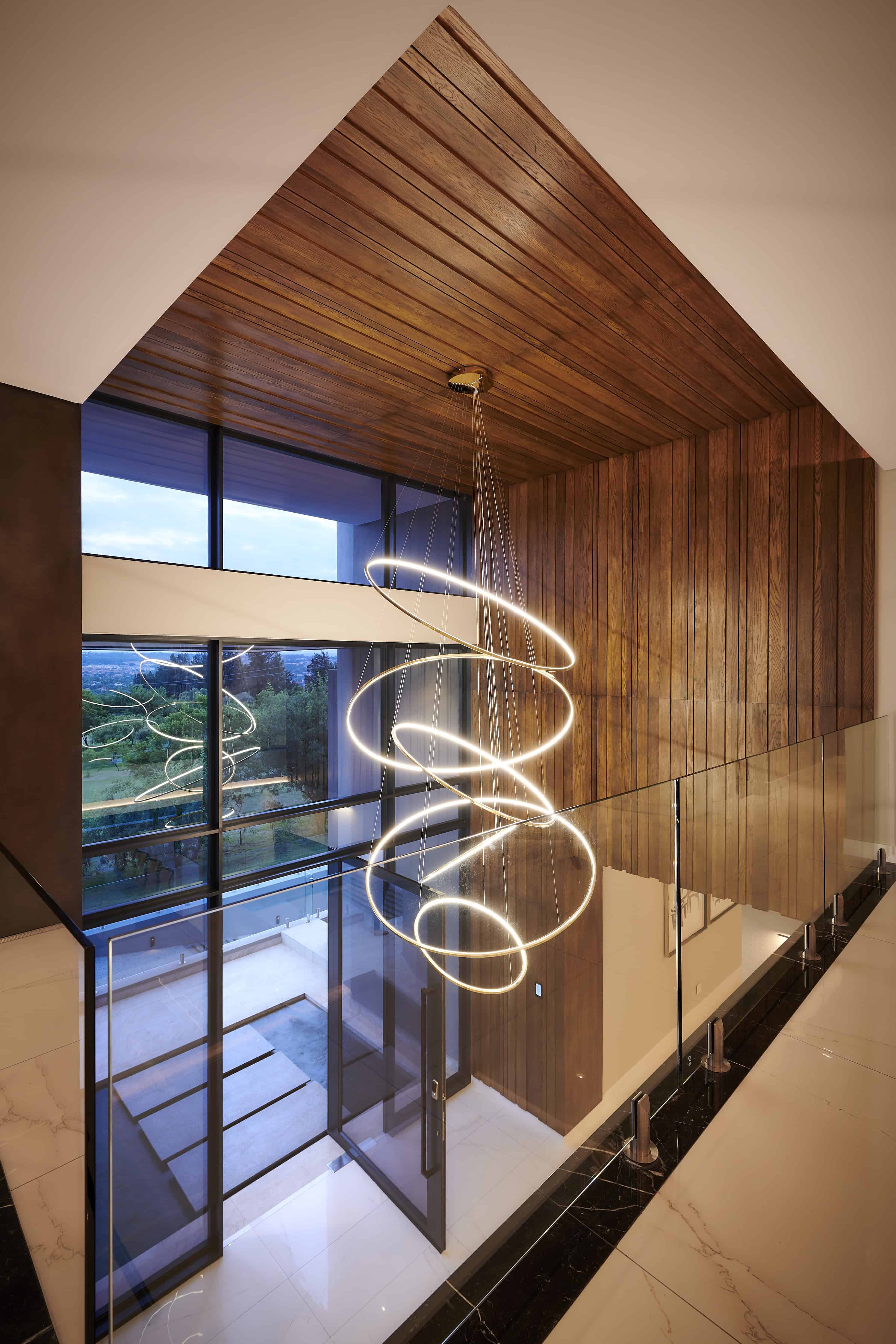 Modern entrance hall with wooden ceiling detail, statement chandelier and large windows by Interior Designer Johannesburg.