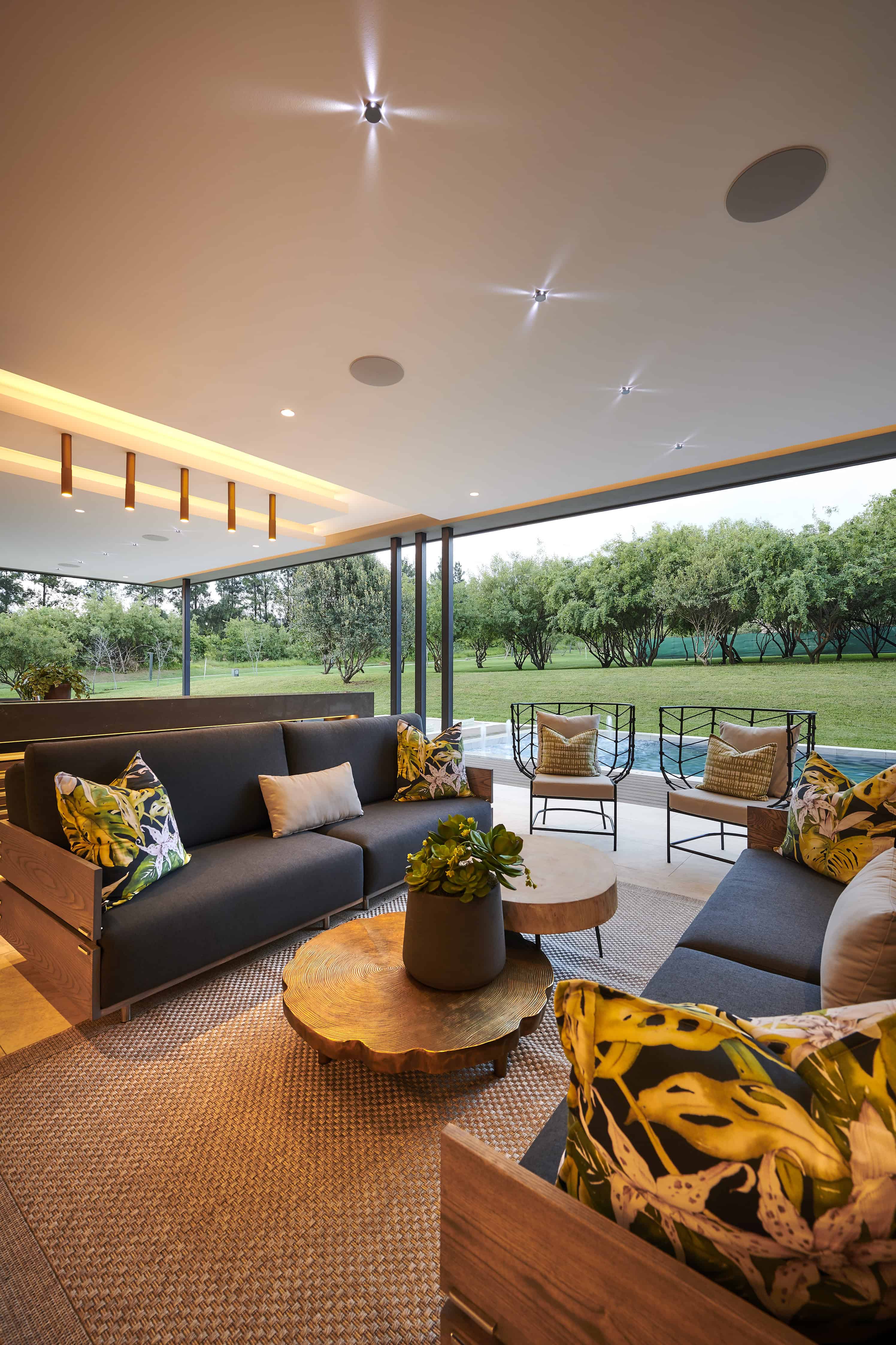 Cozy outdoor lounge with comfortable seating, ceiling lights and panoramic views of the garden designed by Interior Designer Johannesburg.