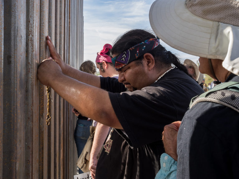 Philip Morales saying a prayer at the border wall in Organ Pipe National Monument.