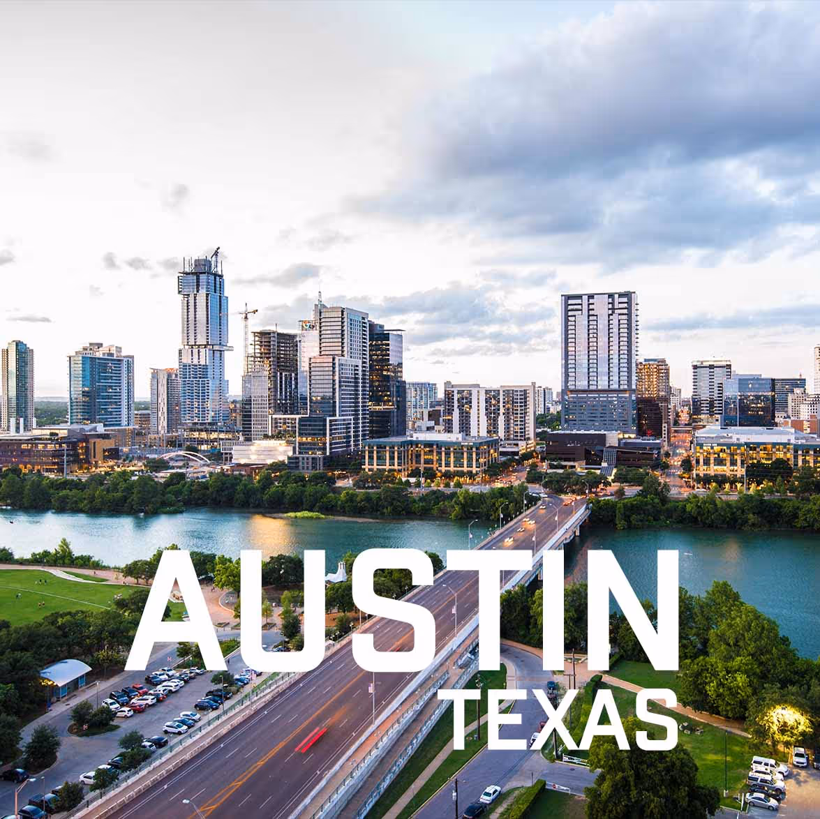 Aerial view of downtown Austin, Texas skyline with river, bridge, and green parks during early evening.