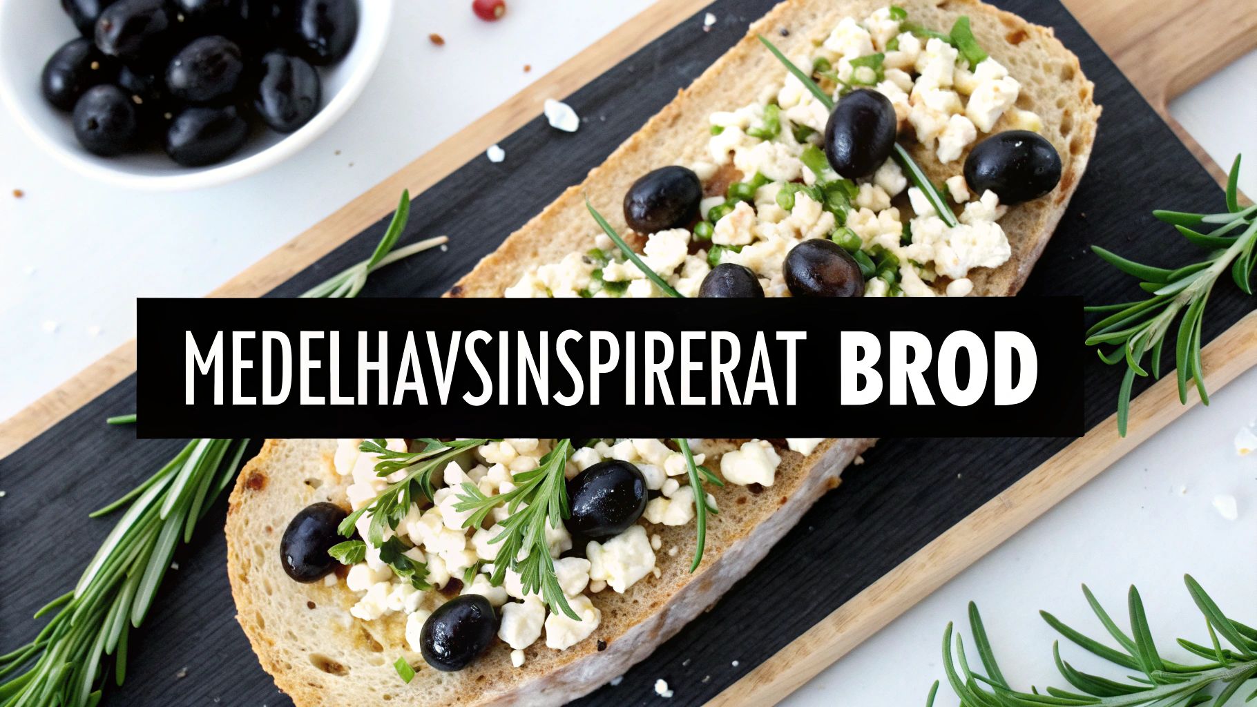 Medelhavsinspirerat bröd toppad med fetaost, svarta oliver, rosmarin och färska örter på skifferbräda