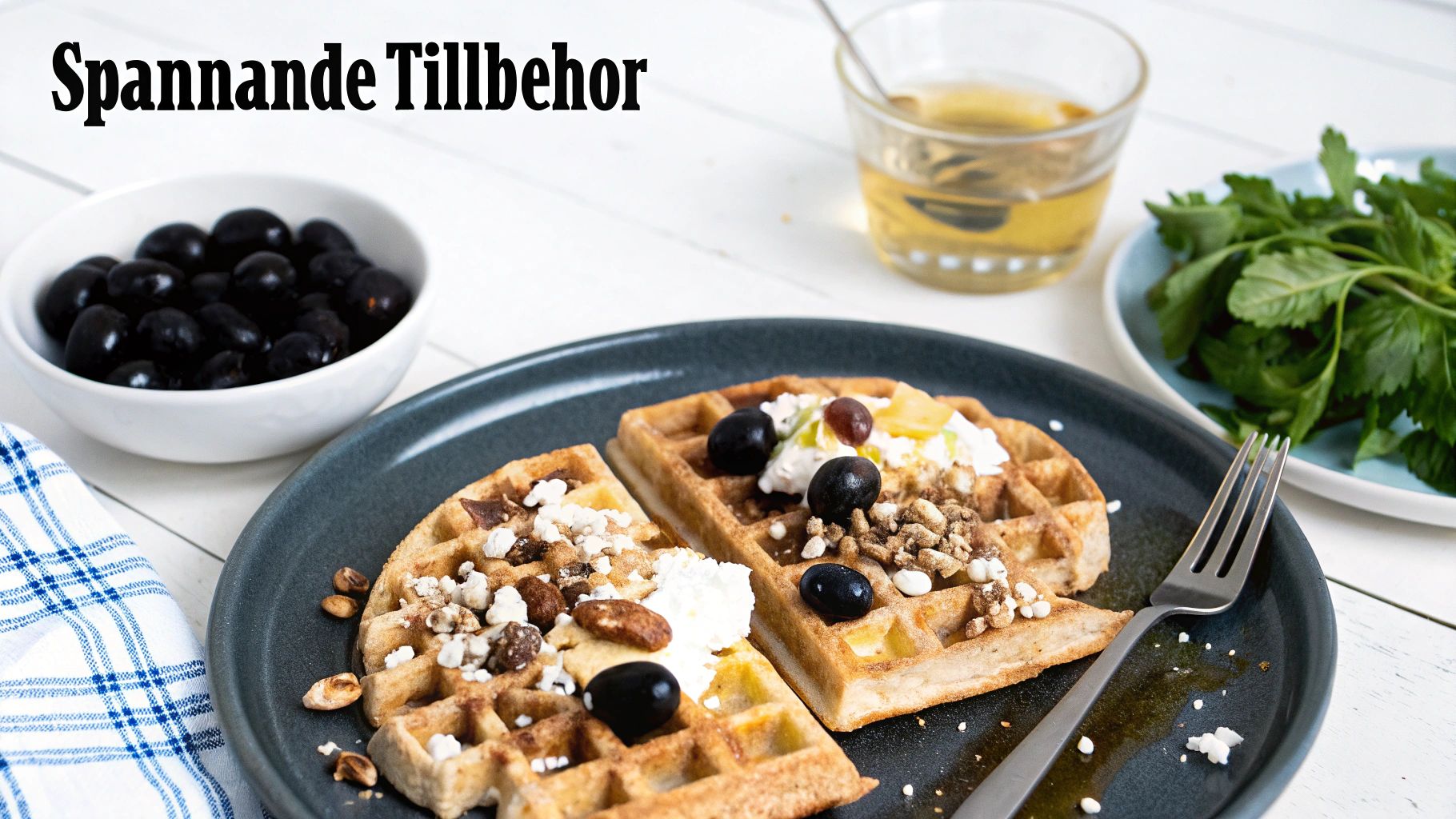 Våfflor med grädde, oliver, nötter och sirap på en tallrik. En skål med oliver och örter i bakgrunden.