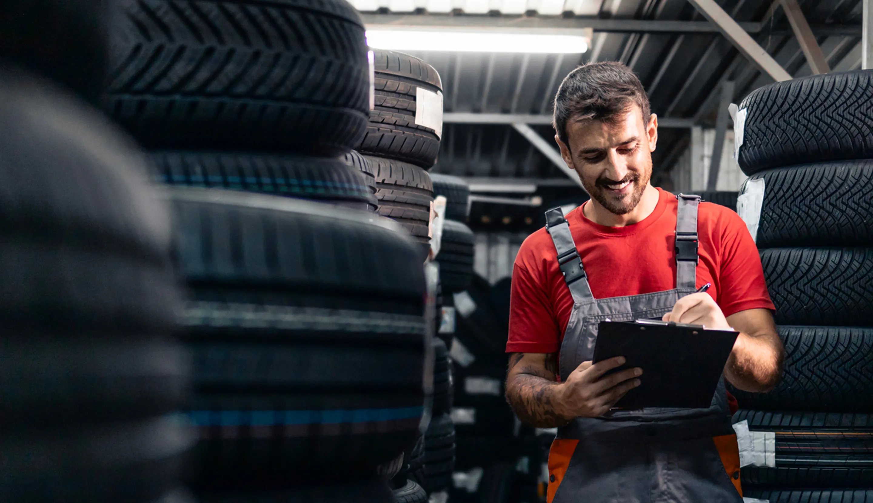 Un garagiste, qui est dans son garage et qui rempli un rapport papier 