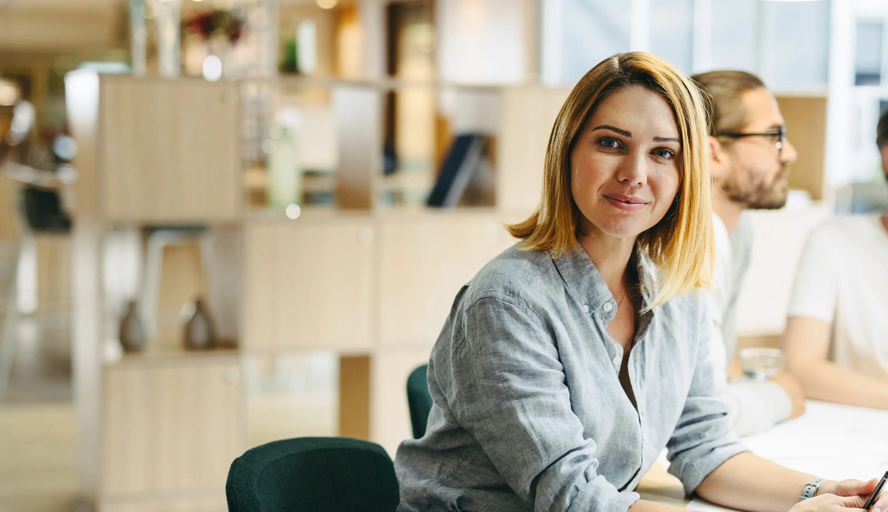 Une femme souriante installée à son bureau qui travaille dans le domaine du conseil