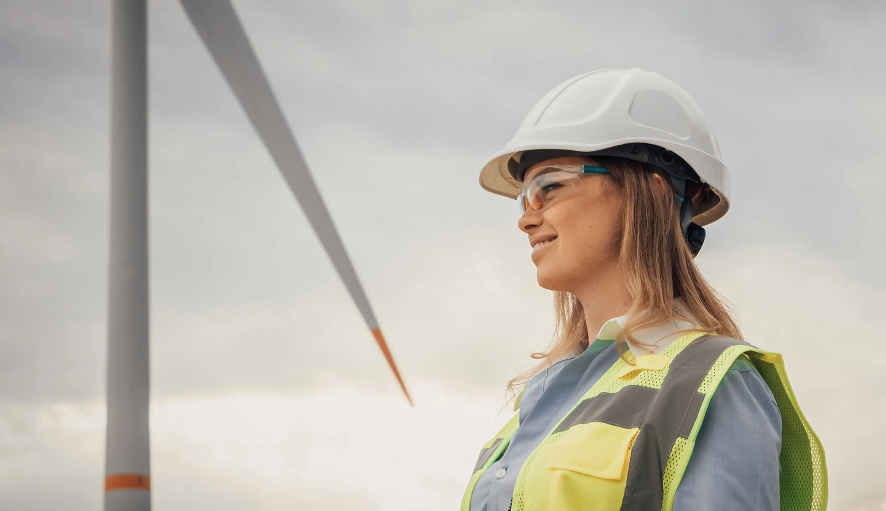 Une femme travaillant dans le domaine de l'énergie regarde une éolienne 