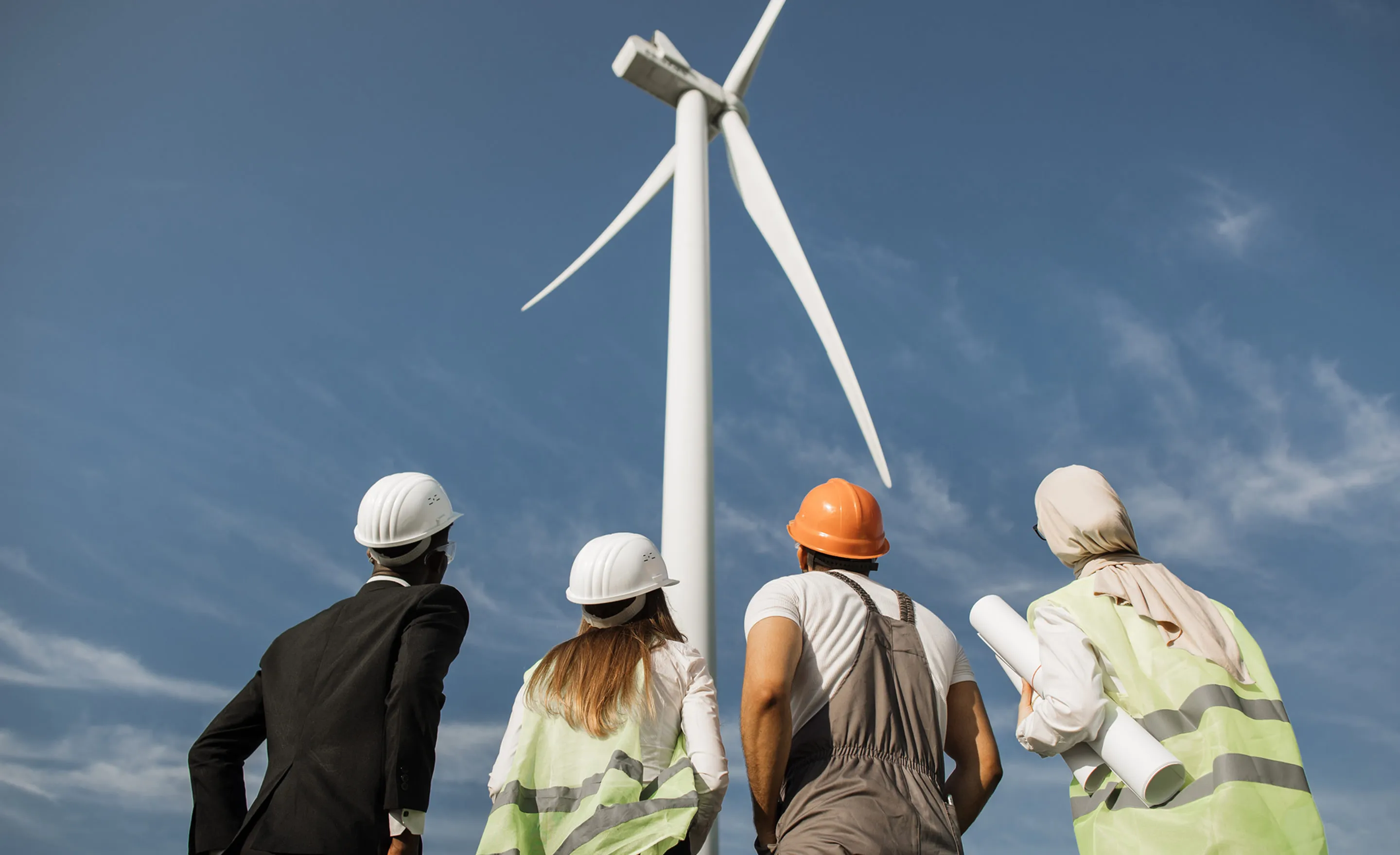 4 personnes qui sont tournés vers une éolienne