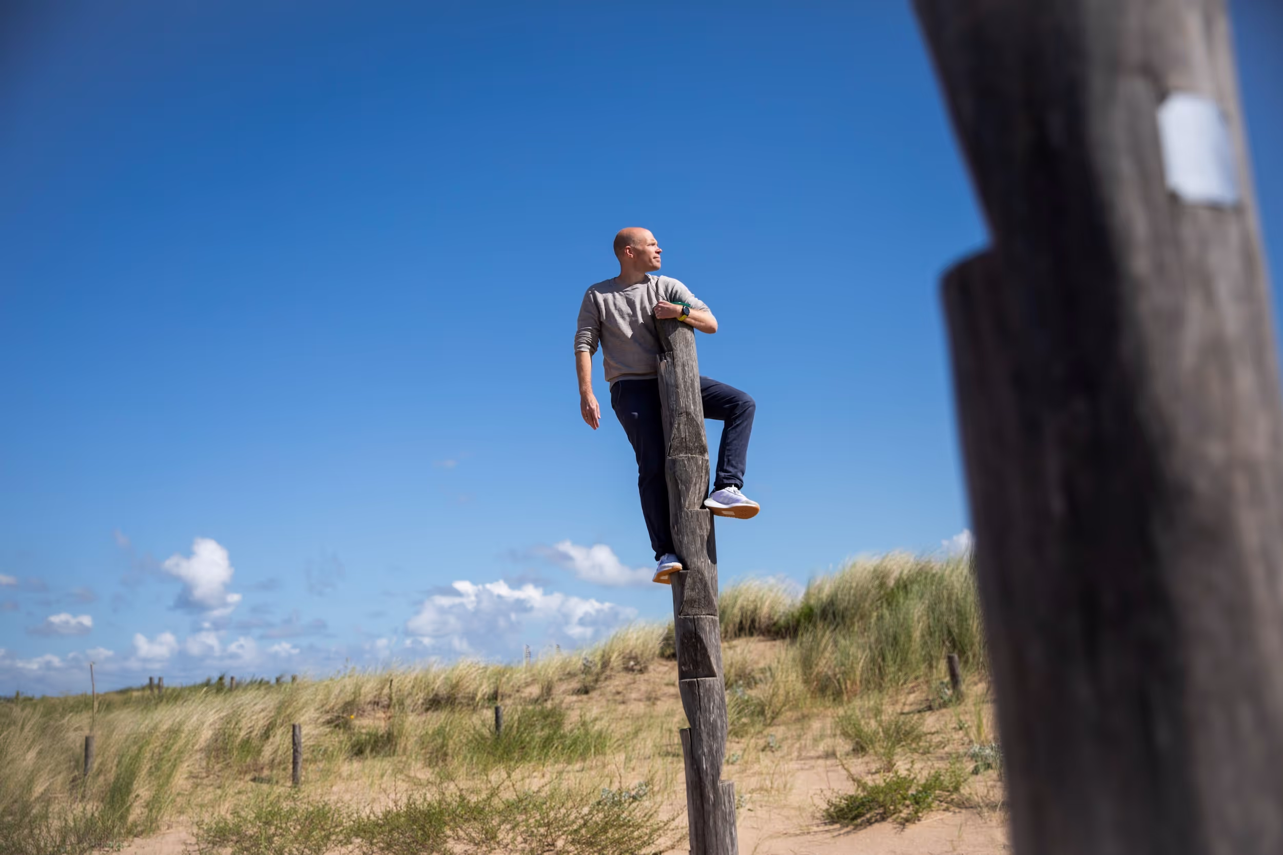 Man die in paal klimt in de duinen.