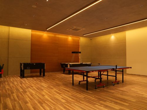 Indoor games room at EIPL Cornerstone featuring table tennis, foosball, and wooden flooring under warm ambient lighting.