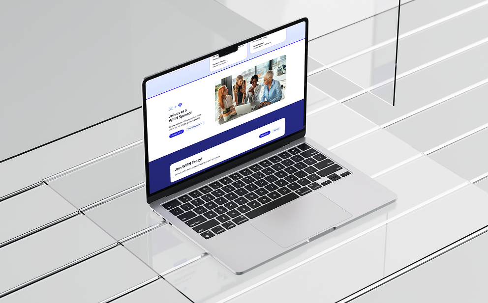 Open laptop on a reflective white surface displaying a webpage with a group of people in a meeting and invitation to join WIPN as a sponsor.