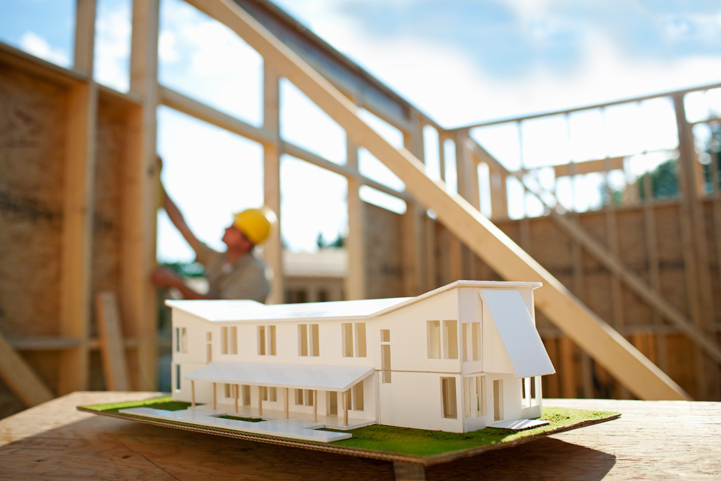 A model home with a construction worker in working in the background