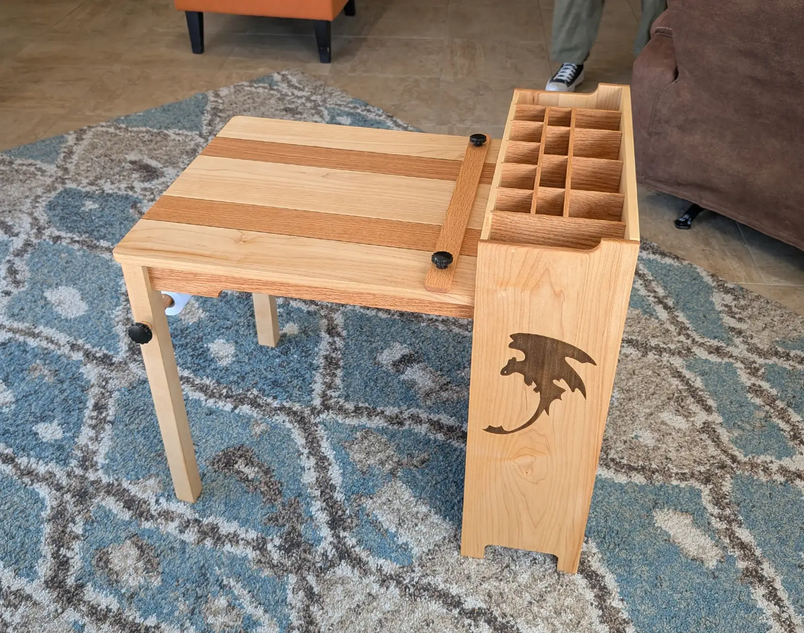 Wooden kids activity table with divided art supply storage, paper roll holder, and custom engraved dragon detail.