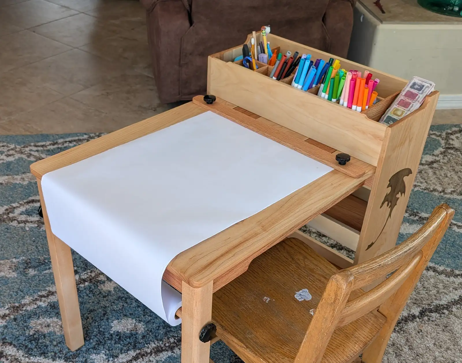 Custom kids art table with paper roll, organized marker storage, watercolor tray, and wooden drawing surface.