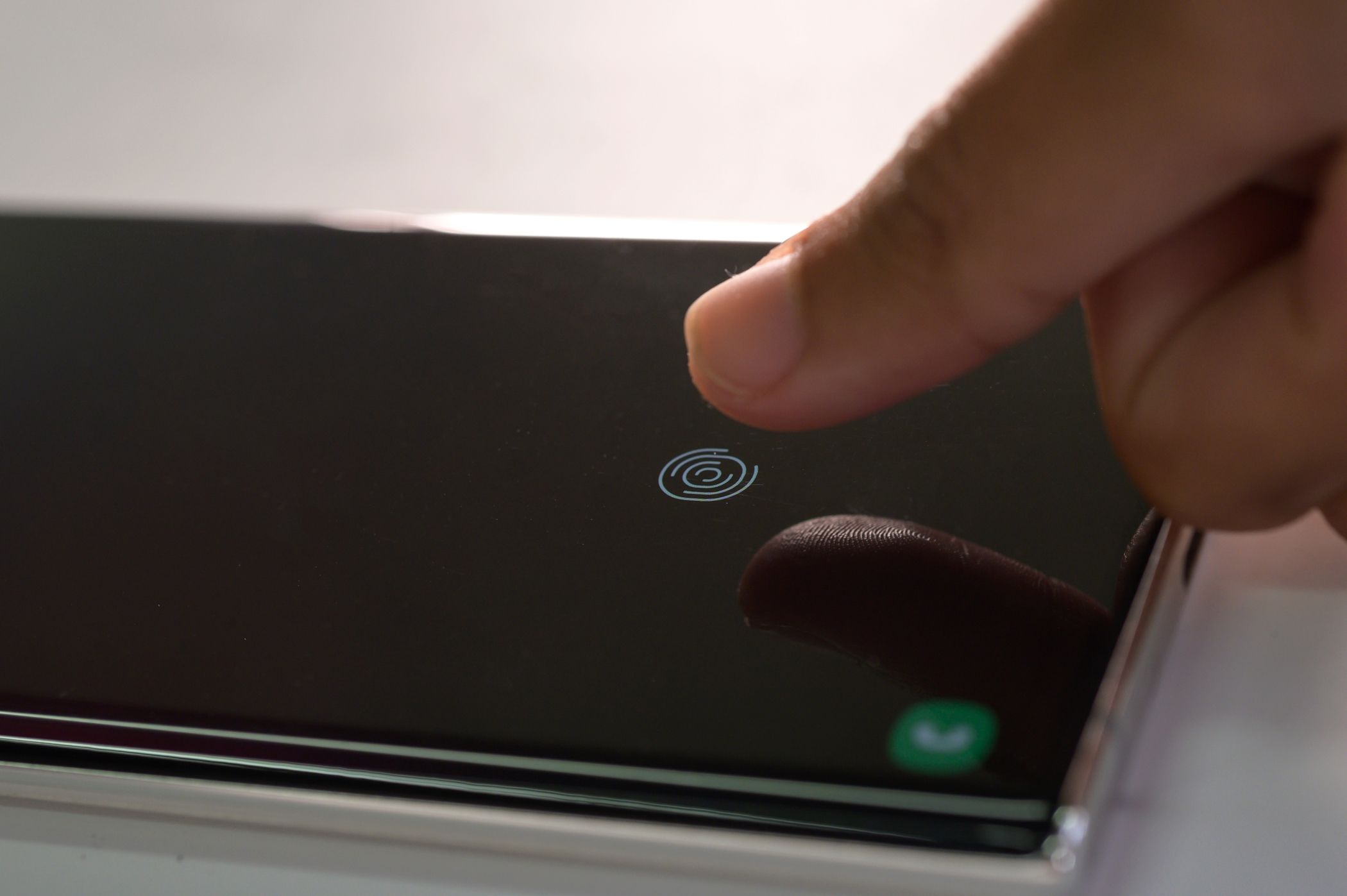 Person unlocking a smartphone using fingerprint authentication.