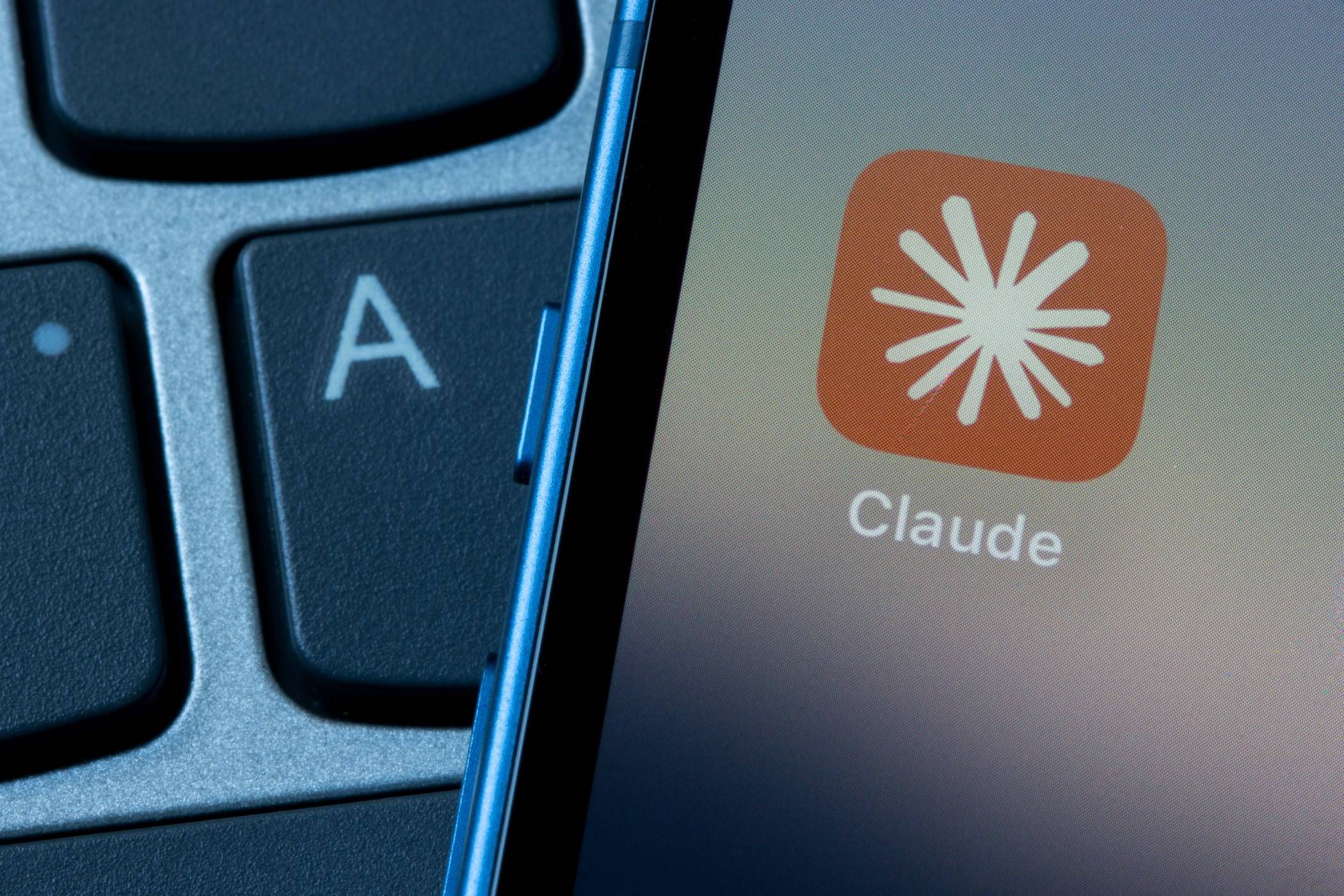 Smartphone showing Claude app near laptop keyboard