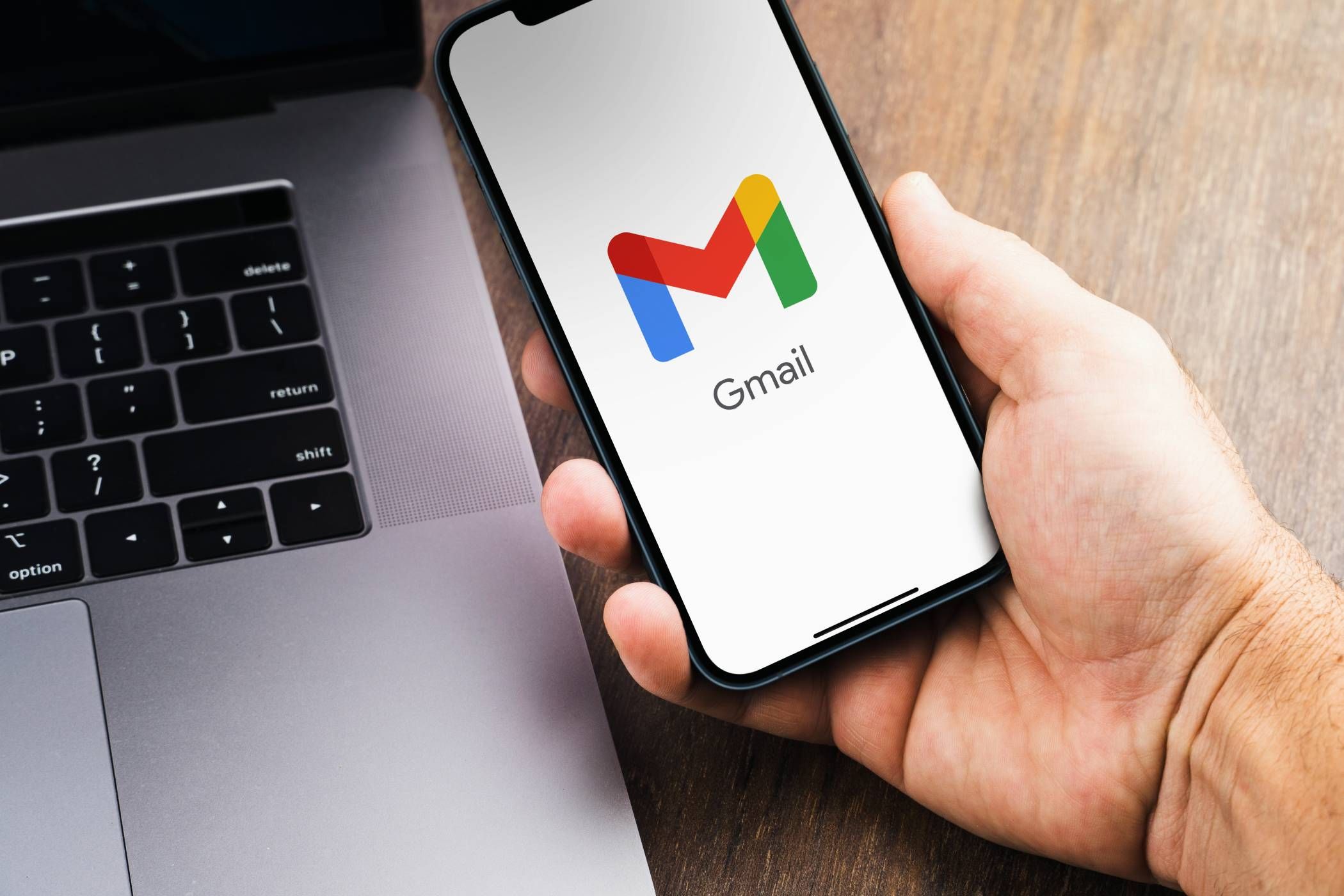 Gmail logo on phone next to an open laptop