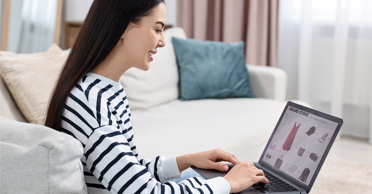 Young woman seating on couch browsing on her laptop