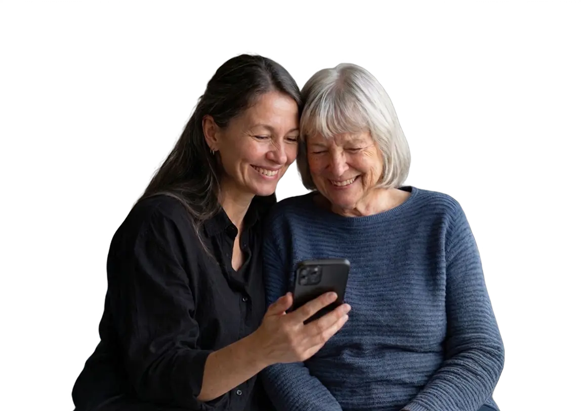 Zwei Frauen, eine jüngere und eine ältere, lächeln gemeinsam beim Blick auf ein Smartphone.