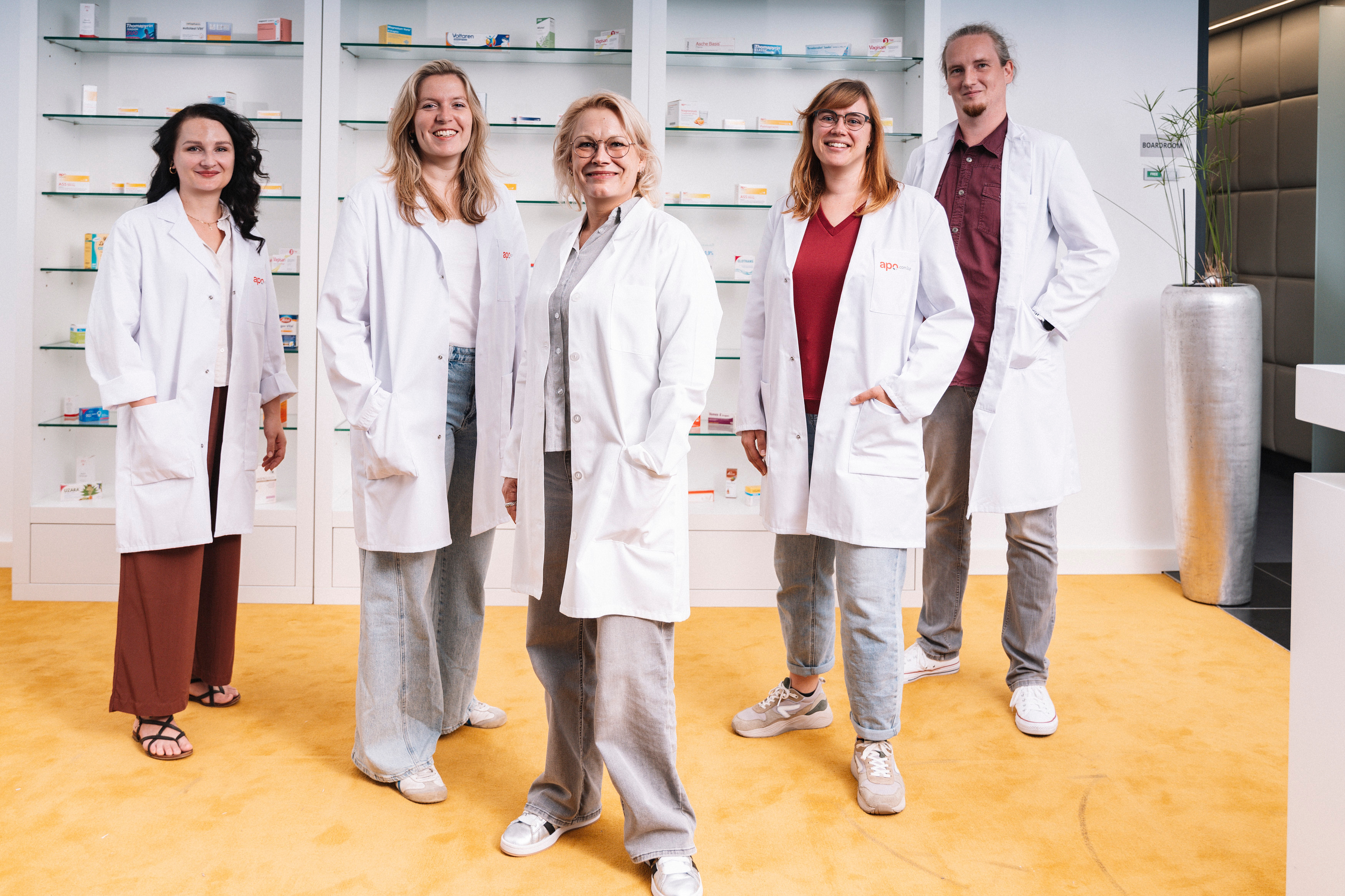 Das Apotheken-Team von apodiscounter: fünf Mitarbeitende in weißen Kitteln in der Apotheke, die Ihre MYA-Medikamentenbestellung bearbeitet