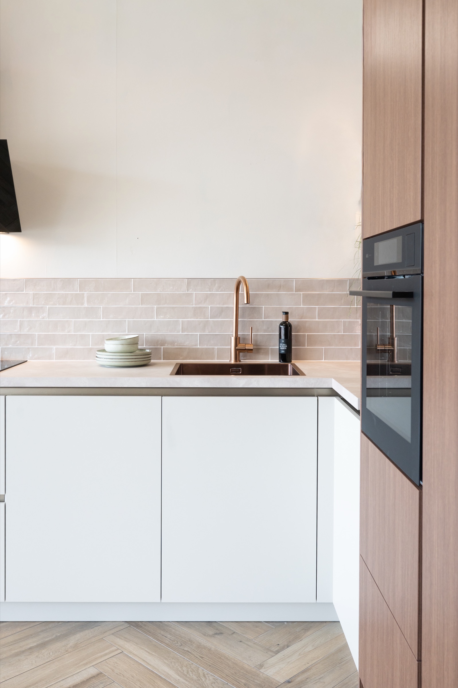 Koperen keukenkraan bij de spoelbak in een witte keuken