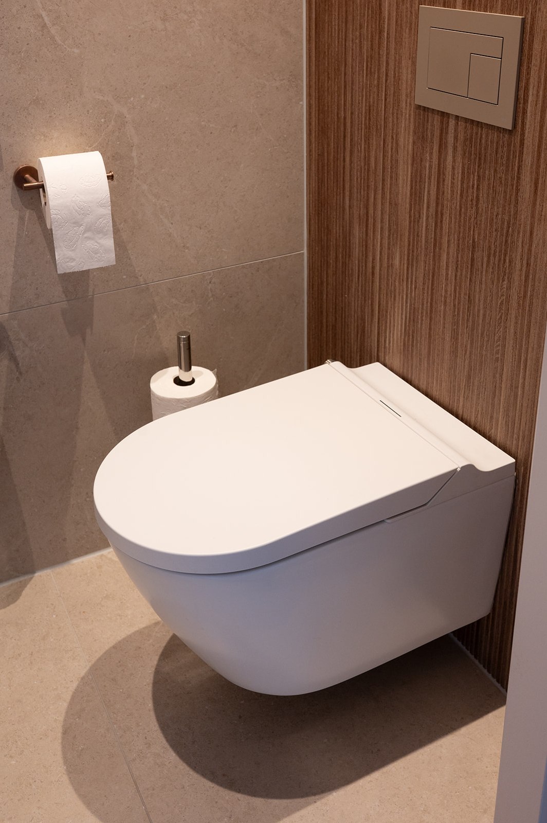 Douche-wc met dik deksel en zijunit tegen een notenhouten wandpaneel