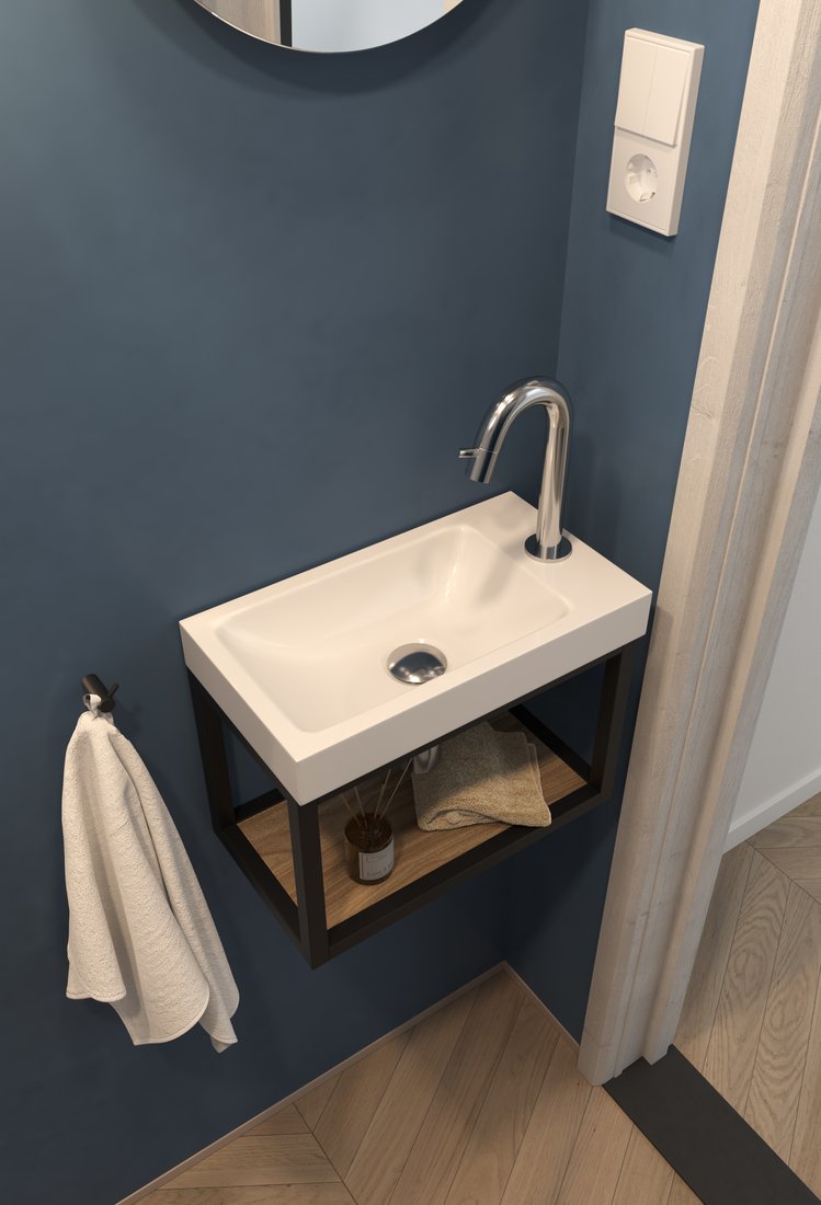 Wit fonteintje op een zwart frame tegen een blauwgrijze wand