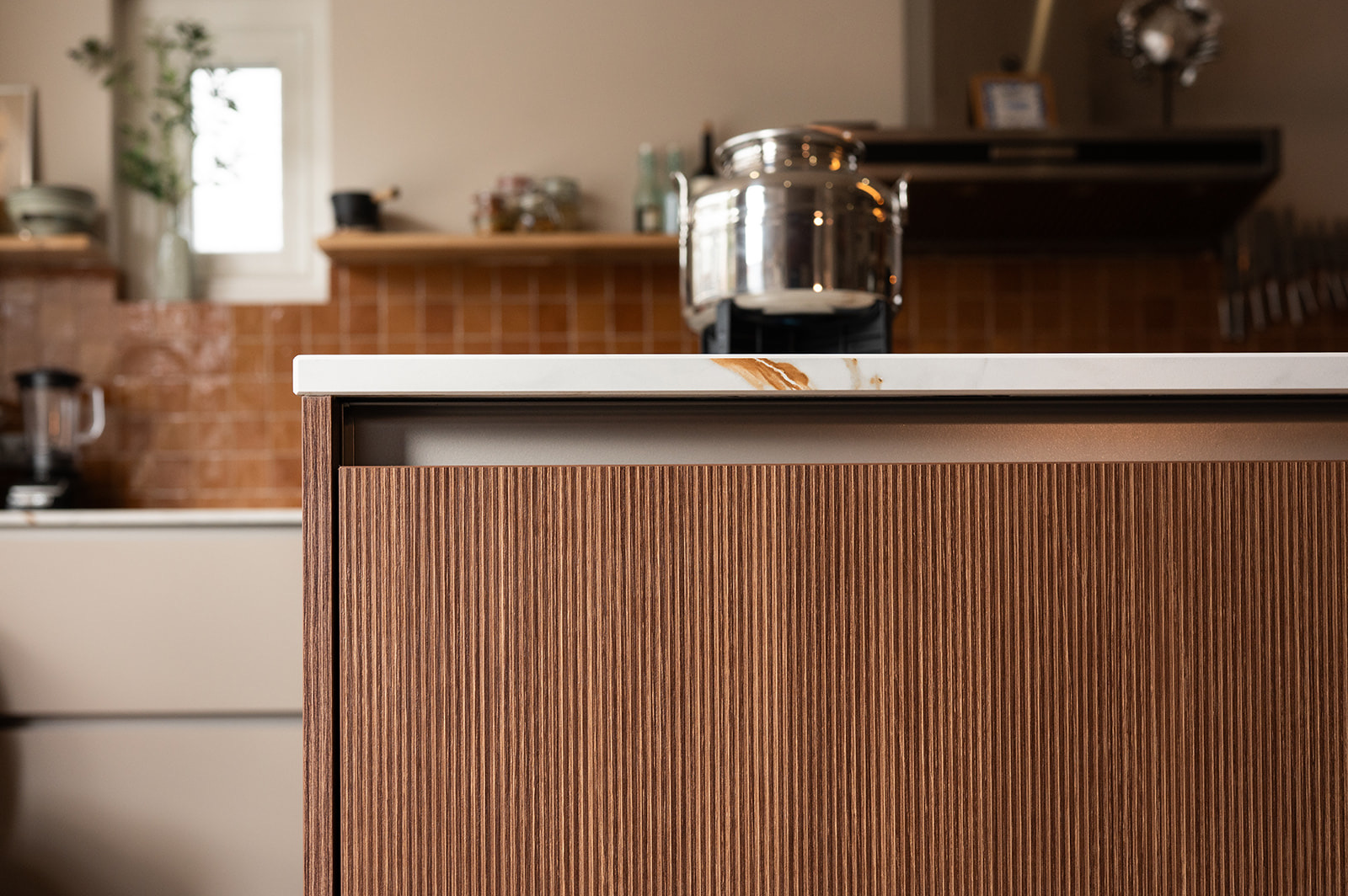 Detail van een houten keuken met walnoot ribbelfront kookeiland en marmerlook werkblad