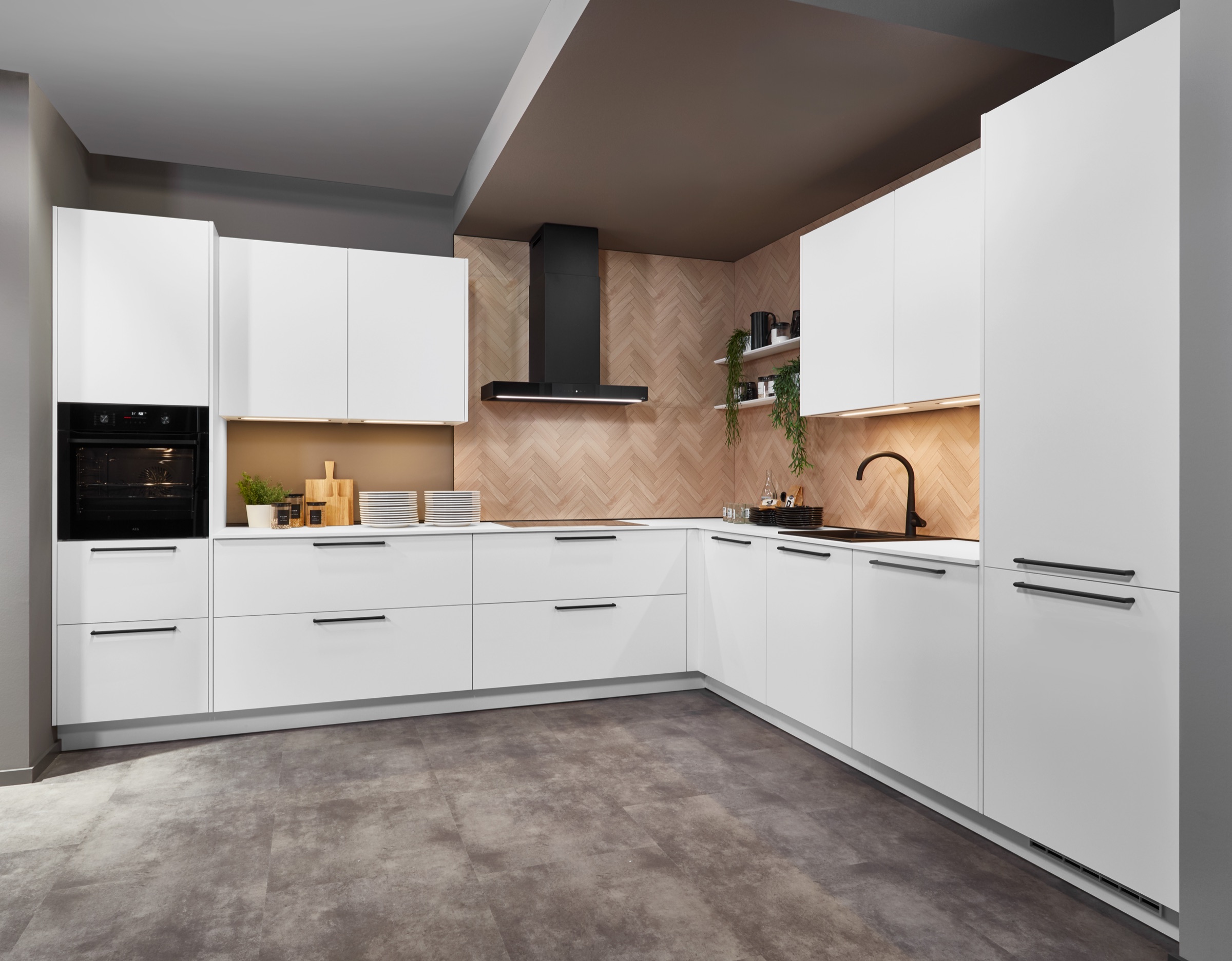 Witte keuken met houten visgraat achterwand en zwarte grepen