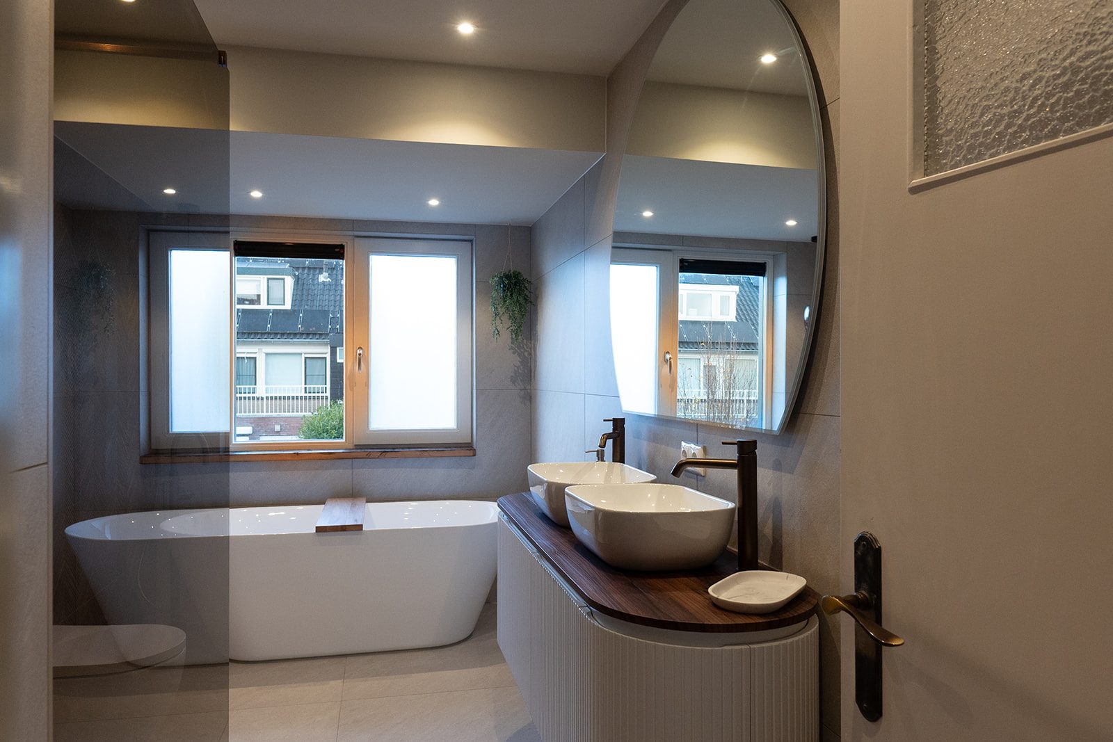 Badkamer met visgraatwand in houtlook, vrijstaand bad en zachte tinten