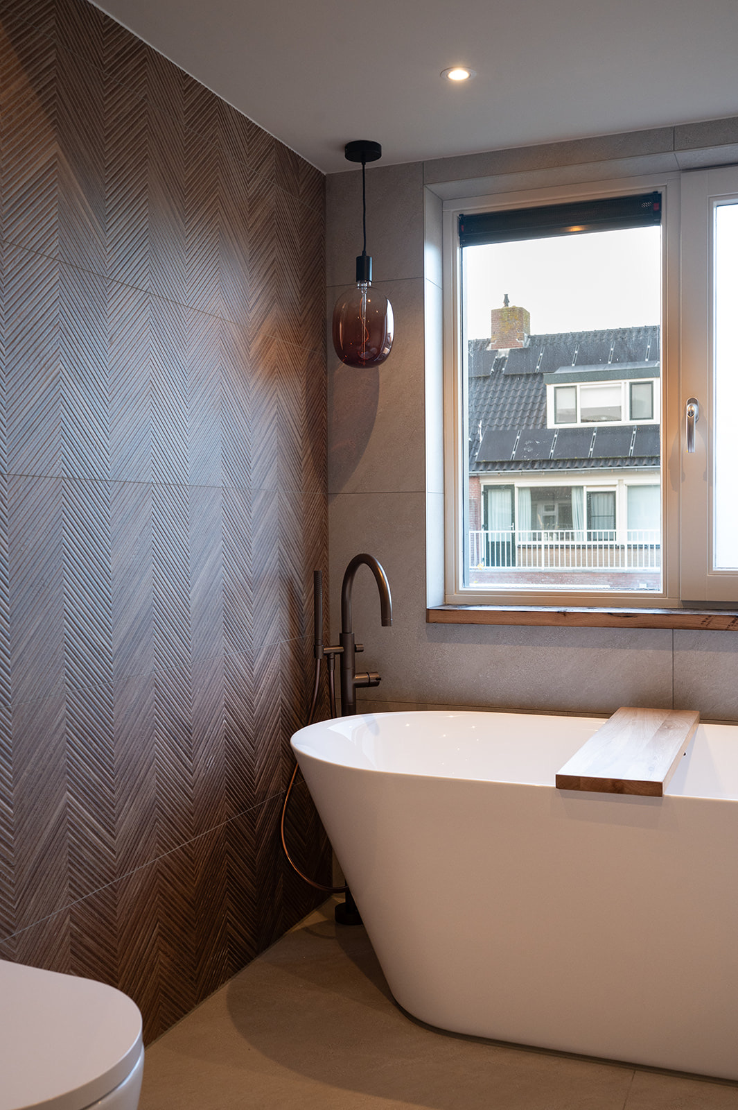 Vrijstaand bad met bronzen vloerkraan en hanglamp