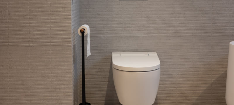 Hangtoilet met stortknop tegen een wand met reliëftegels