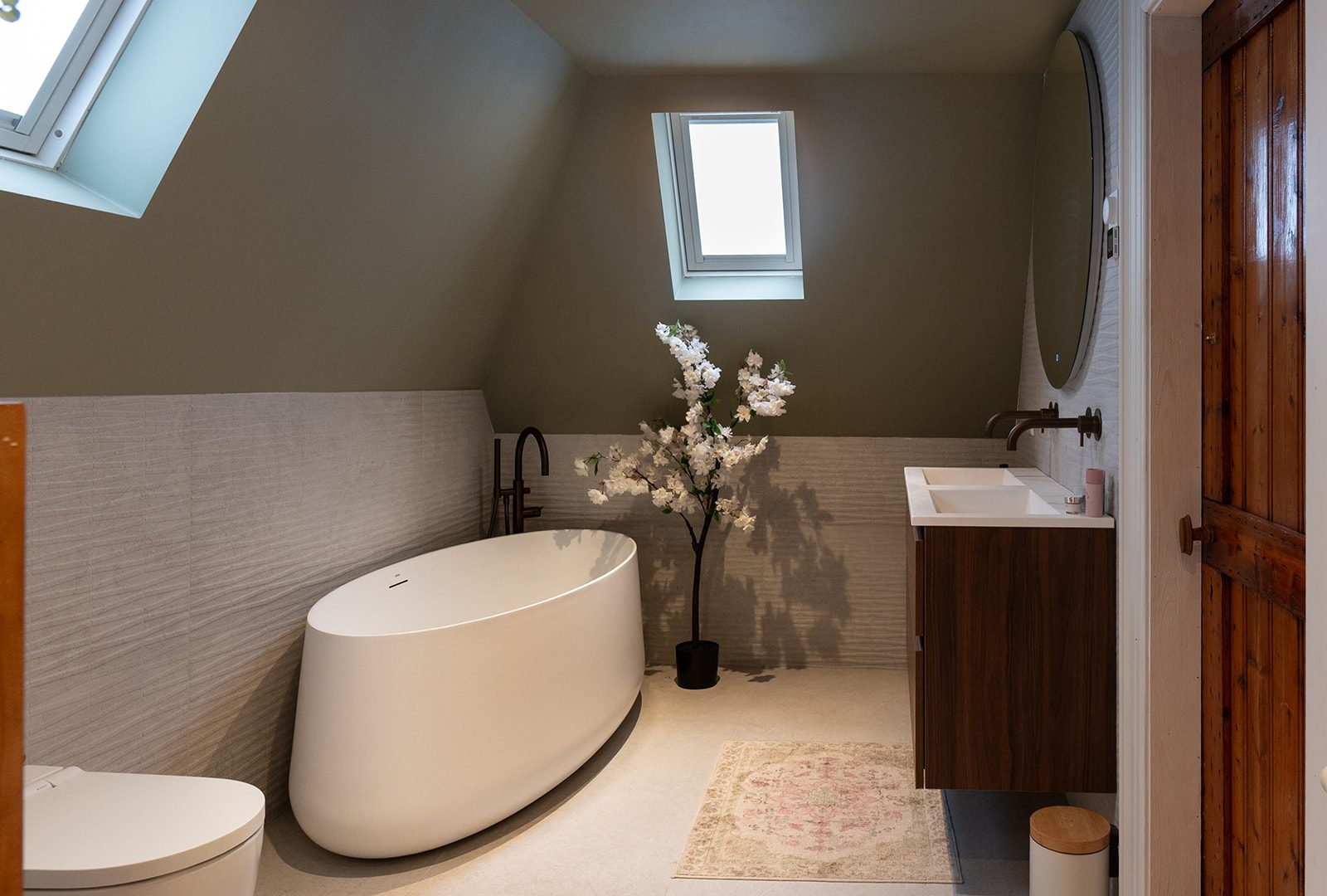 Zolderbadkamer met lichte reliëftegels, olijfgroene wand en houten badmeubel
