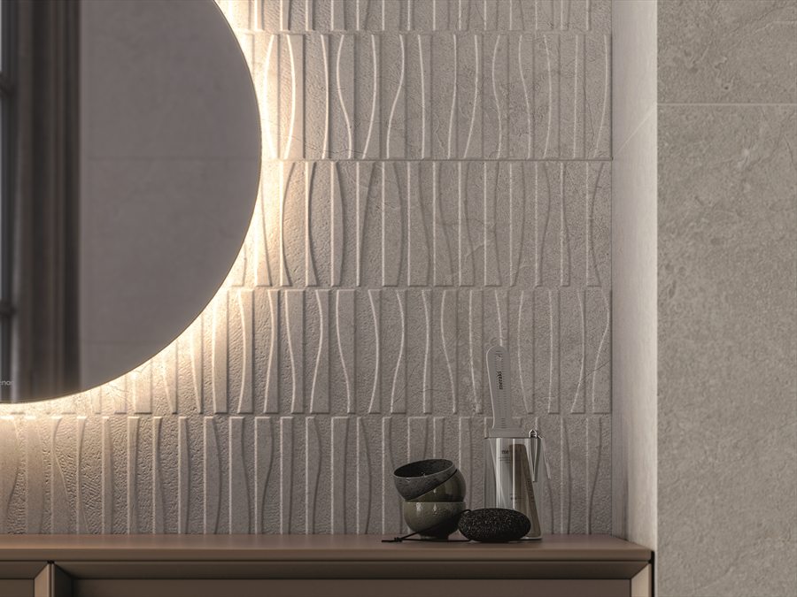 Lichte reliëftegels met golfmotief achter een ronde spiegel met verlichting