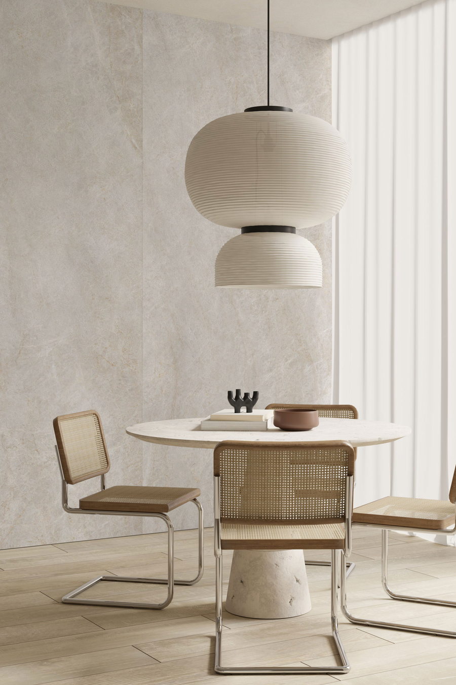 Ronde eettafel met rieten stoelen voor een wand in steenlook, op een lichte vloer met houtnerf