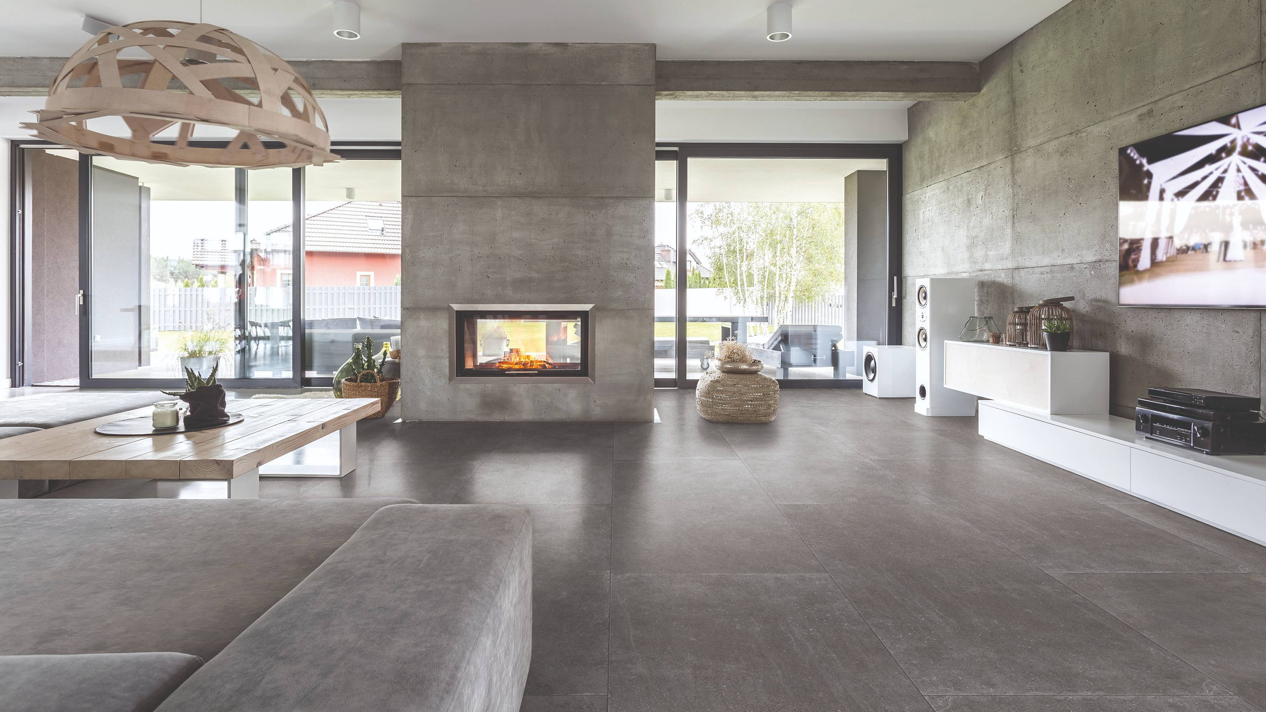 Woonkamer met een grootformaat tegelvloer in betonlook en een ingebouwde haard in een betonnen wand