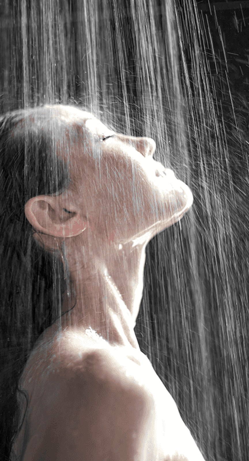 Iemand onder een regendouche met neervallend water, in zwart-wit
